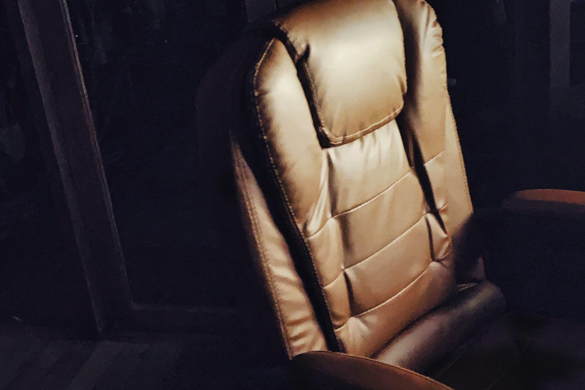 A brown leather chair is lit against darkness.