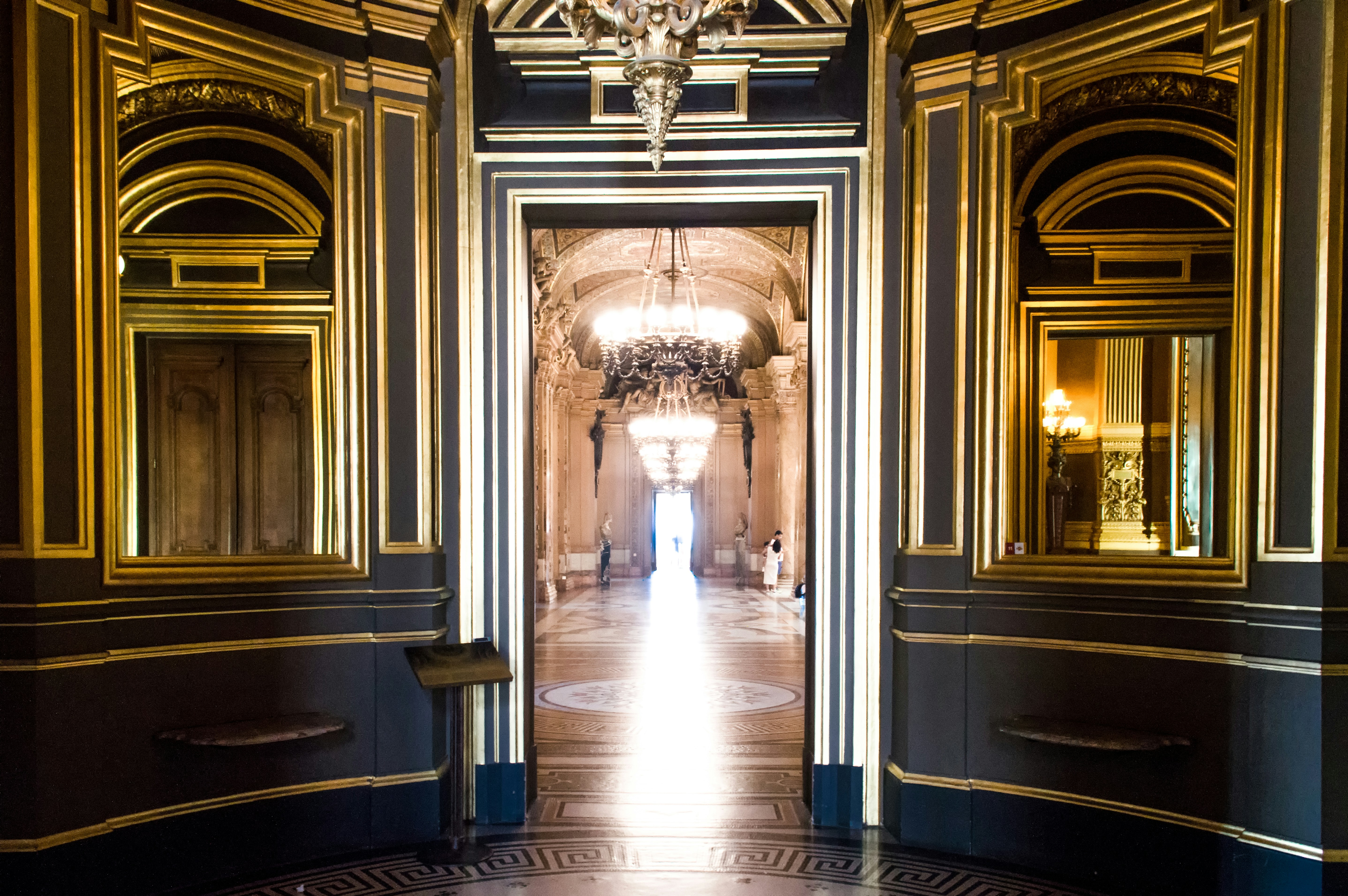 A grand hallway with ornate gilded frames is visible