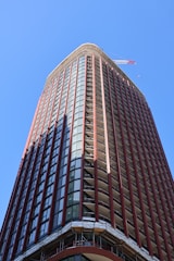 A tall building reaches towards the bright blue sky.