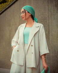 Woman poses stylishly in a light-colored outfit.
