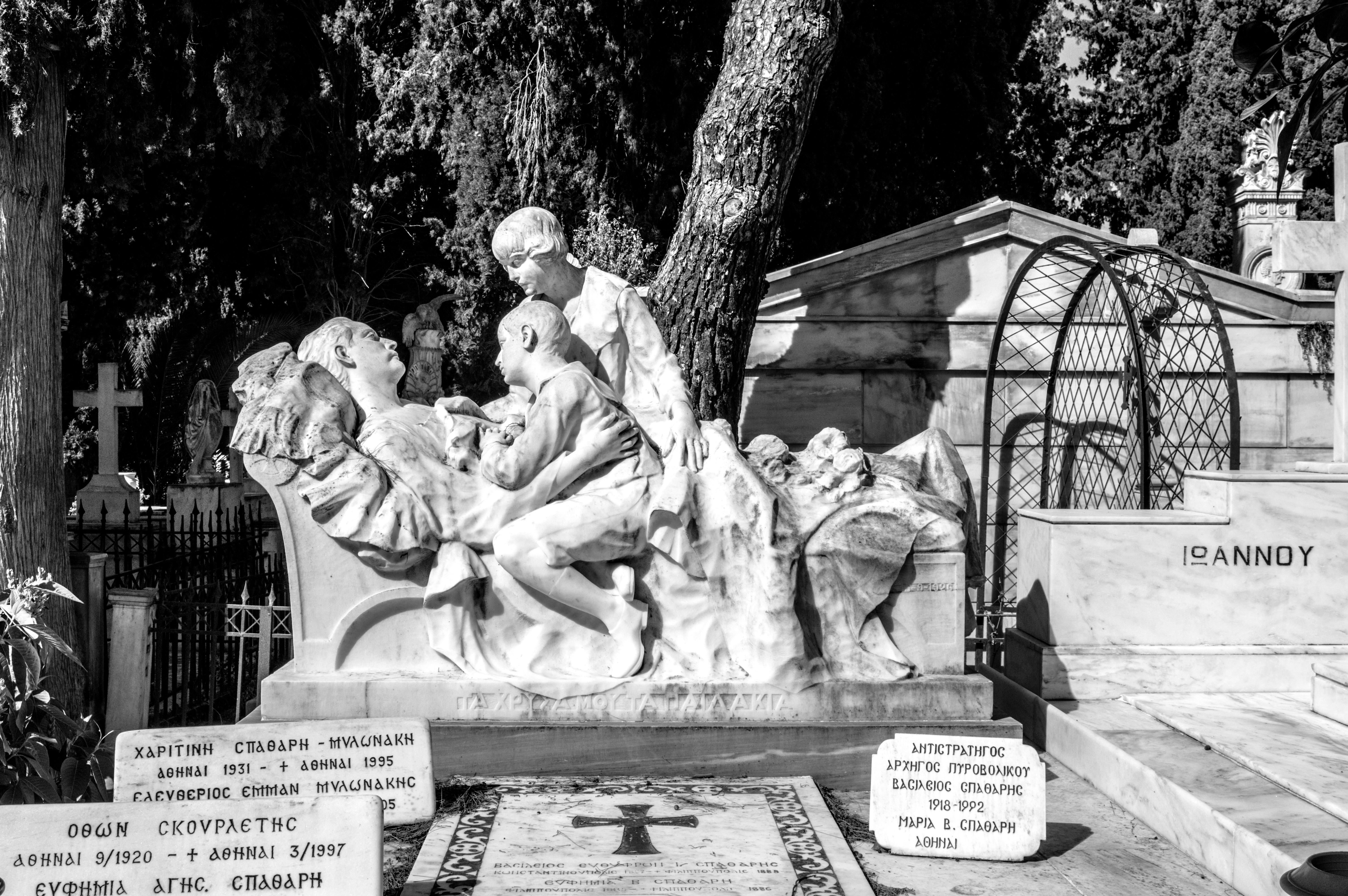 Statue of figures on a tombstone in a graveyard.