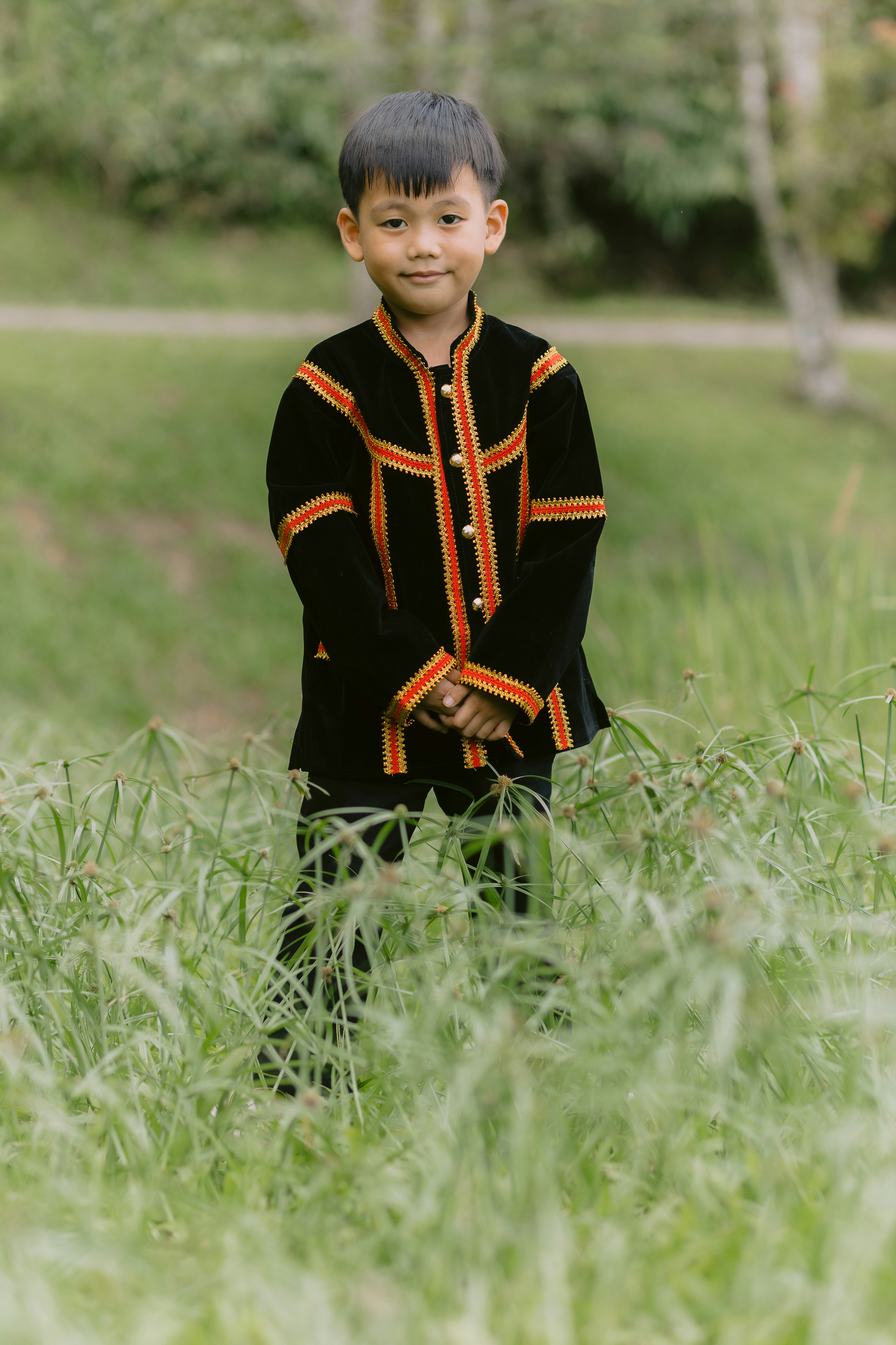 A young boy in traditional attire smiles.