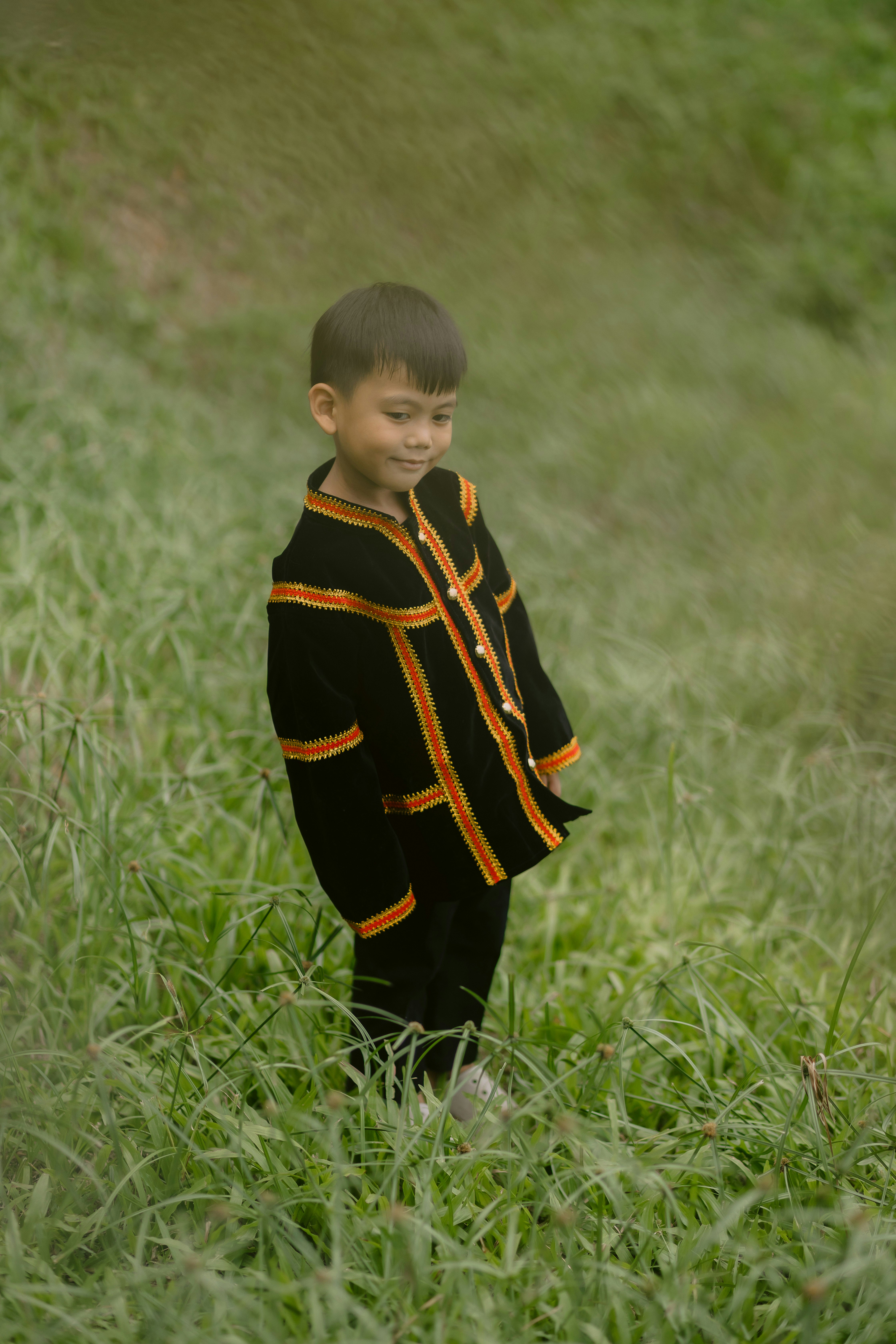 A young boy smiles while standing in grass.