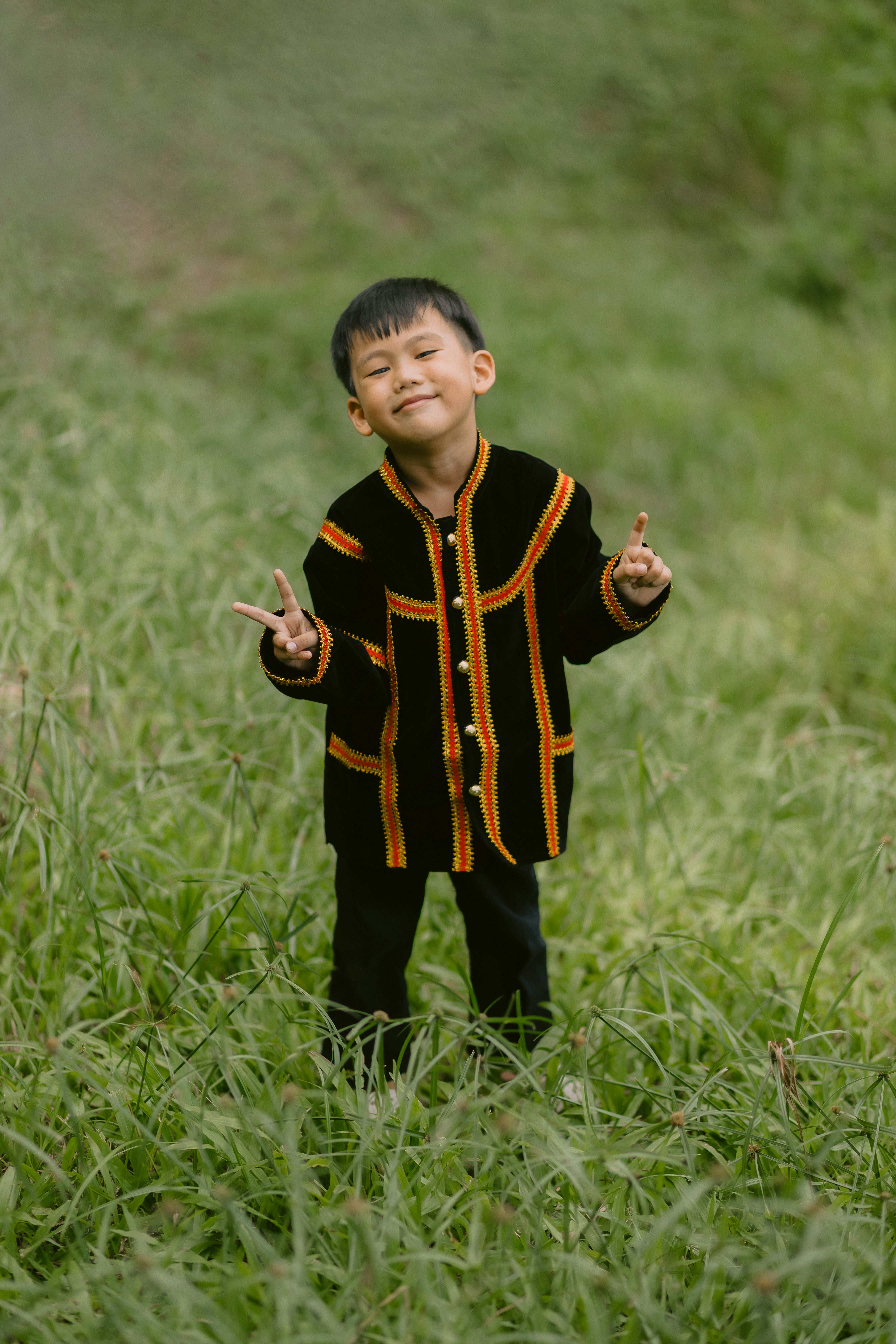 A boy gives peace signs in a field.