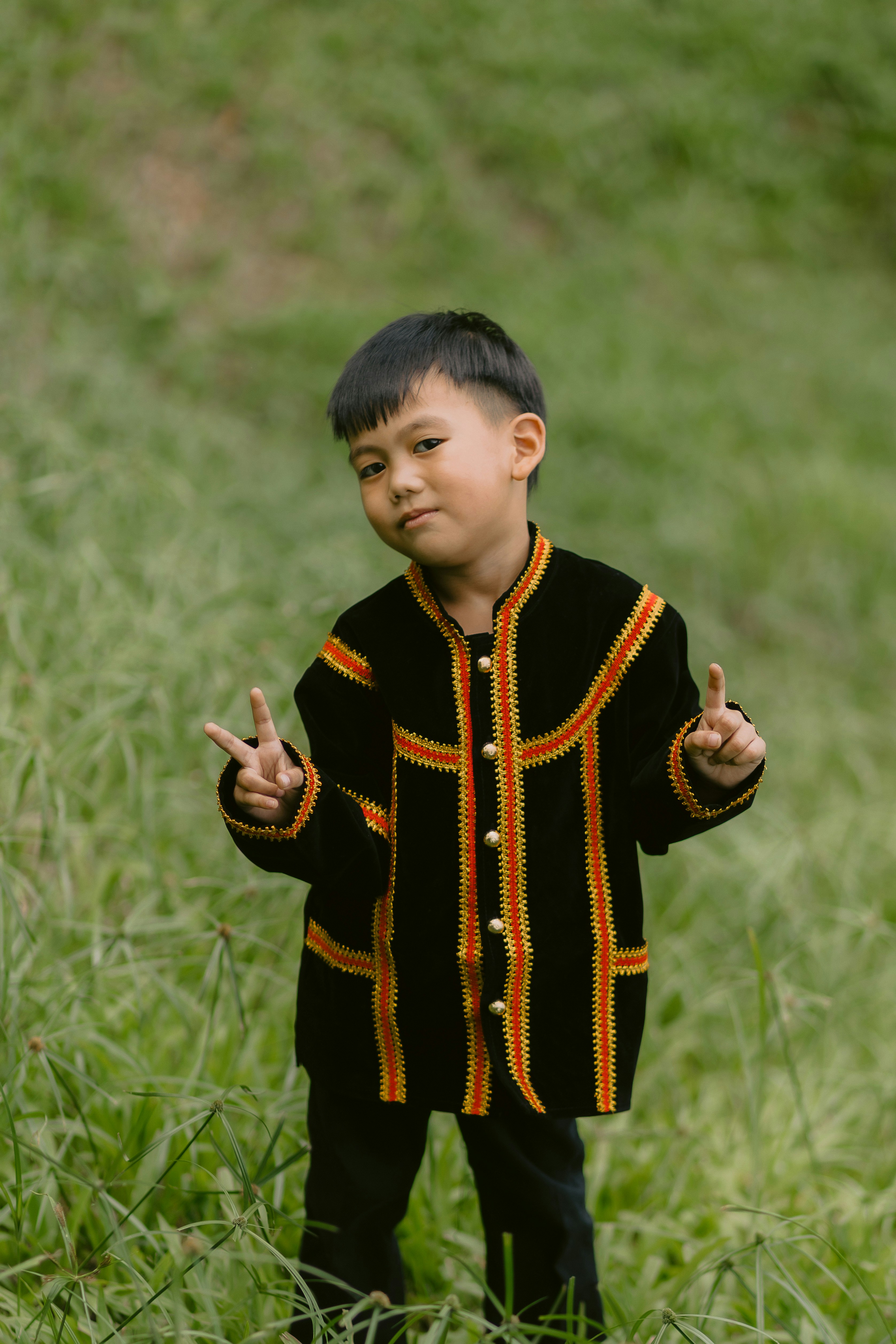 Young boy in traditional clothing gives peace signs.