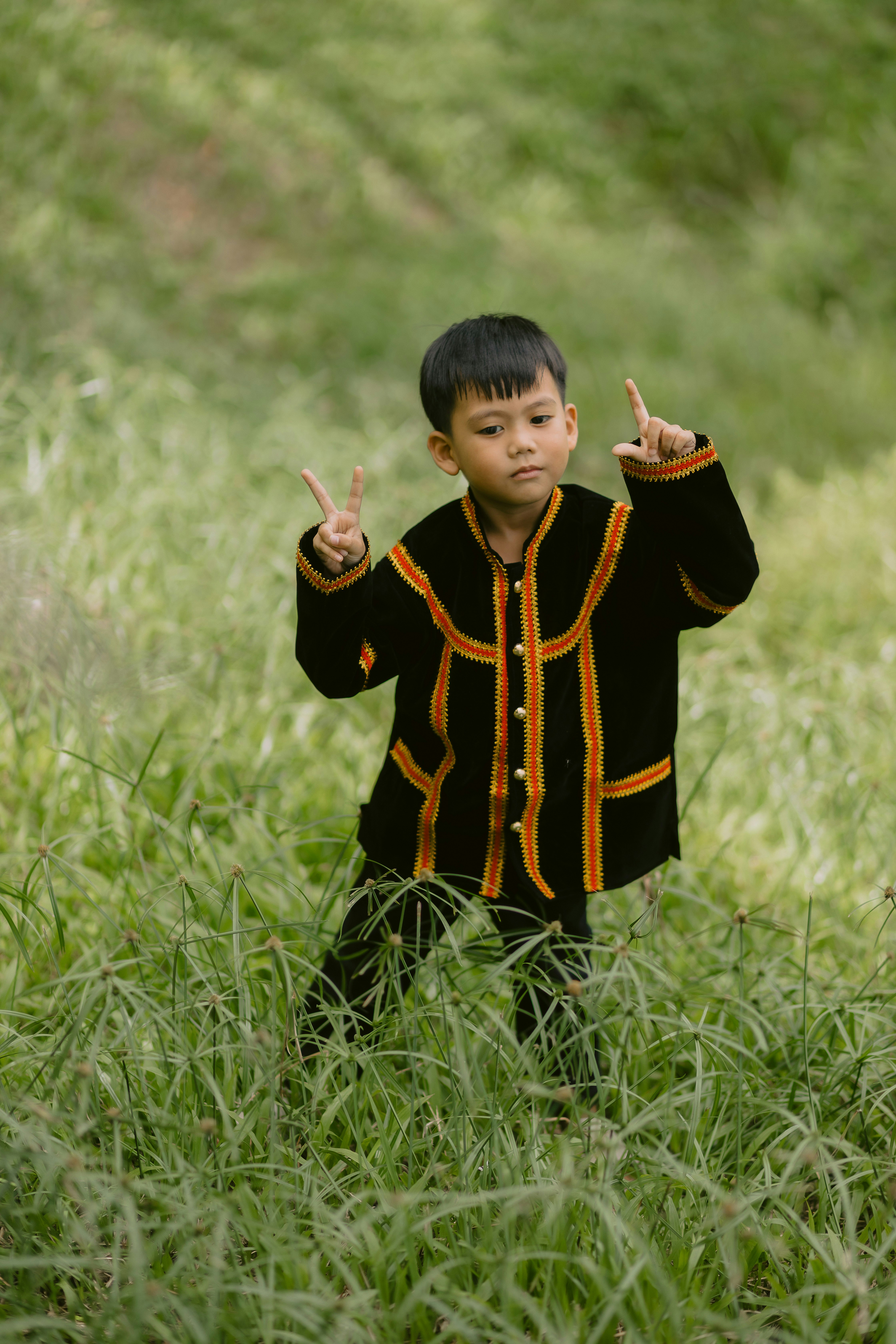 A boy in traditional clothes makes a peace sign.