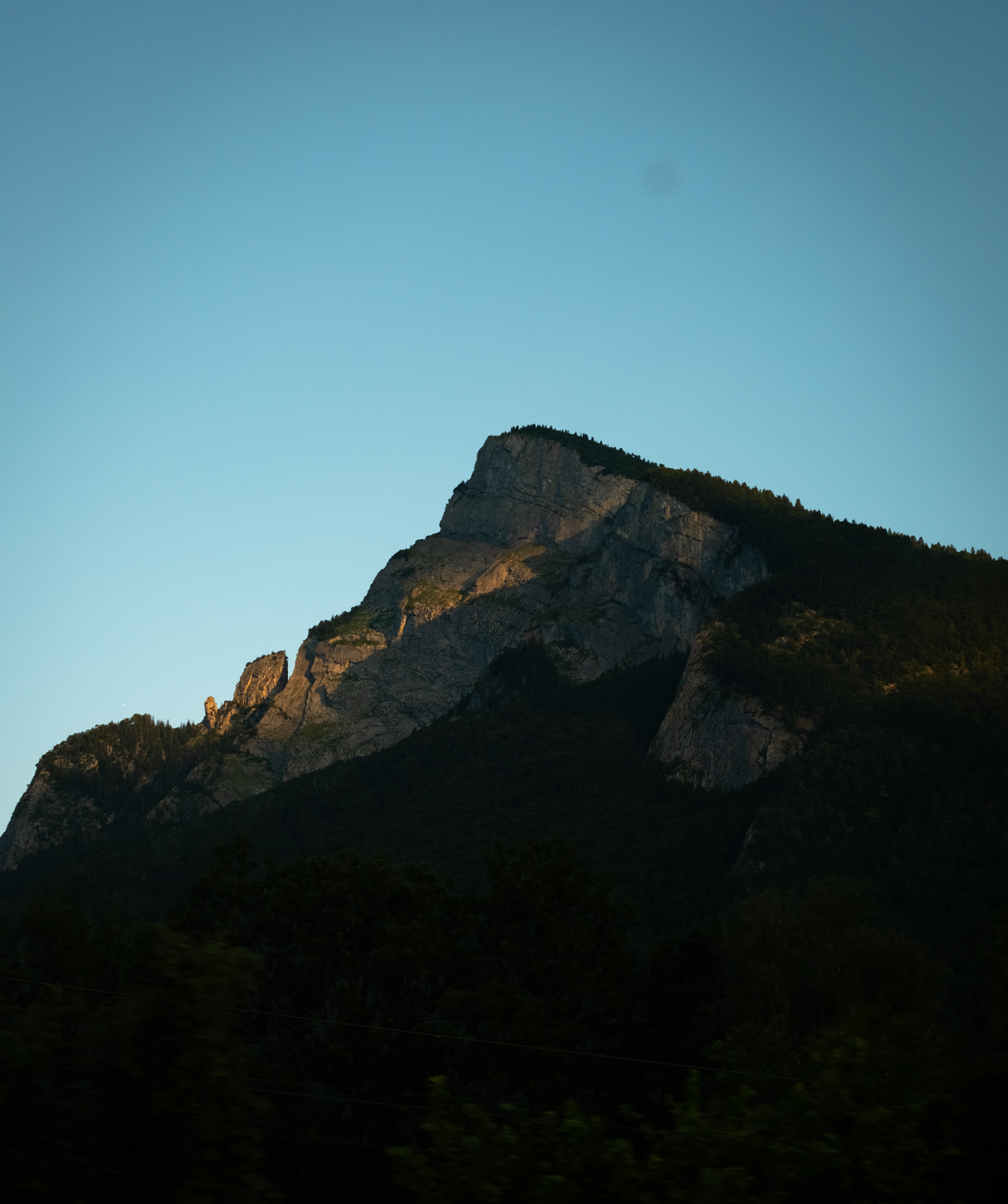 Mountain peak illuminated by sunlight under blue sky.