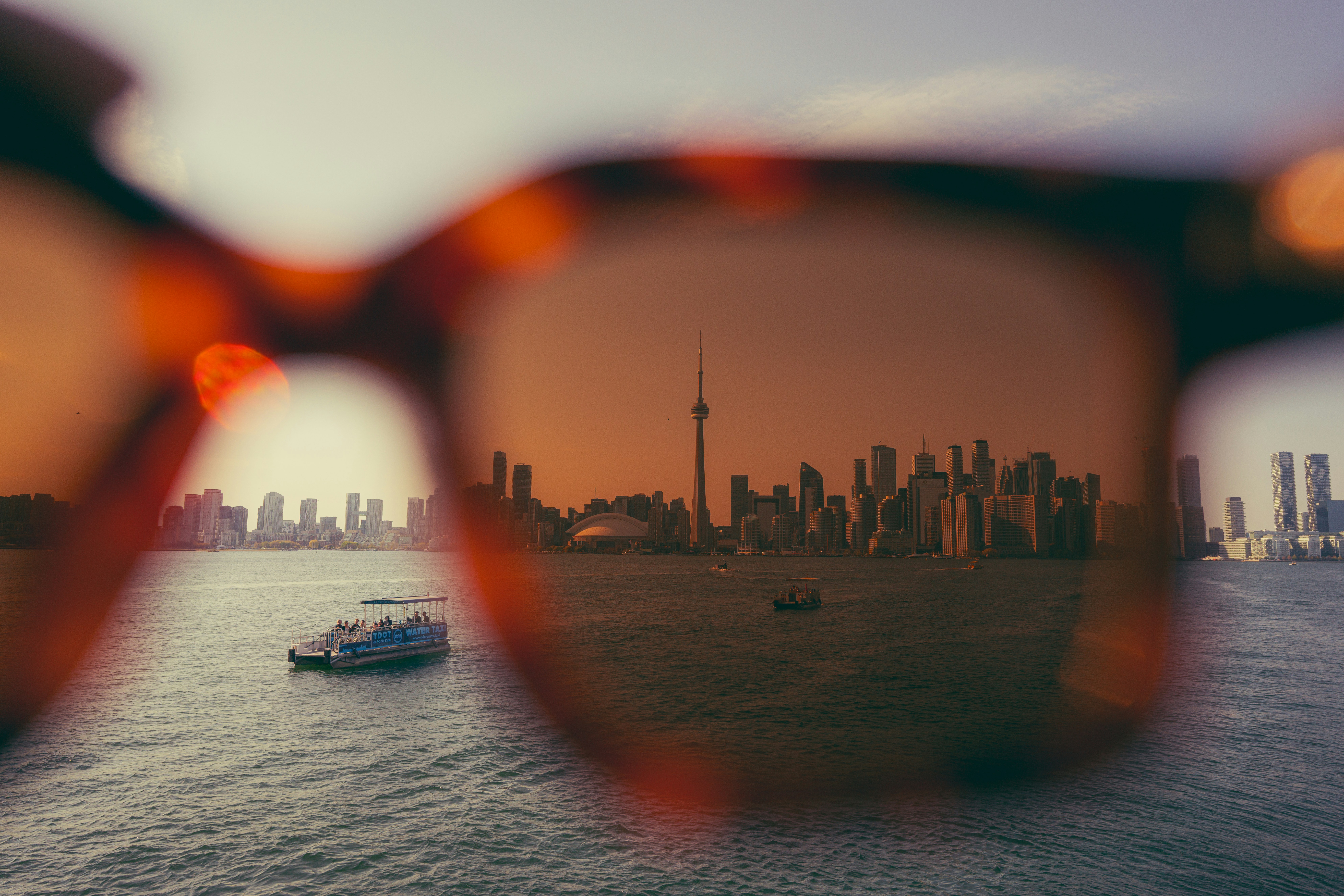 Cityscape reflections seen through sunglasses on water.