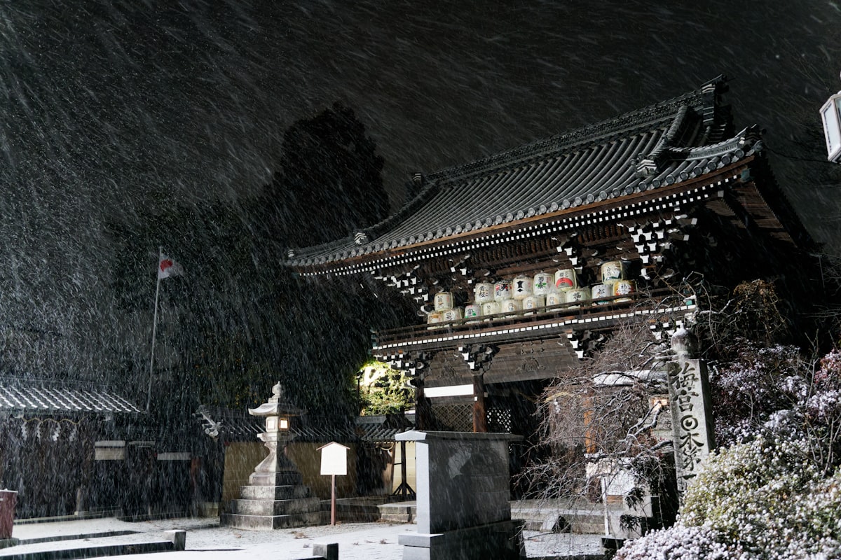 Kyoto December — temple standing in falling snow at night in quiet winter atmosphere