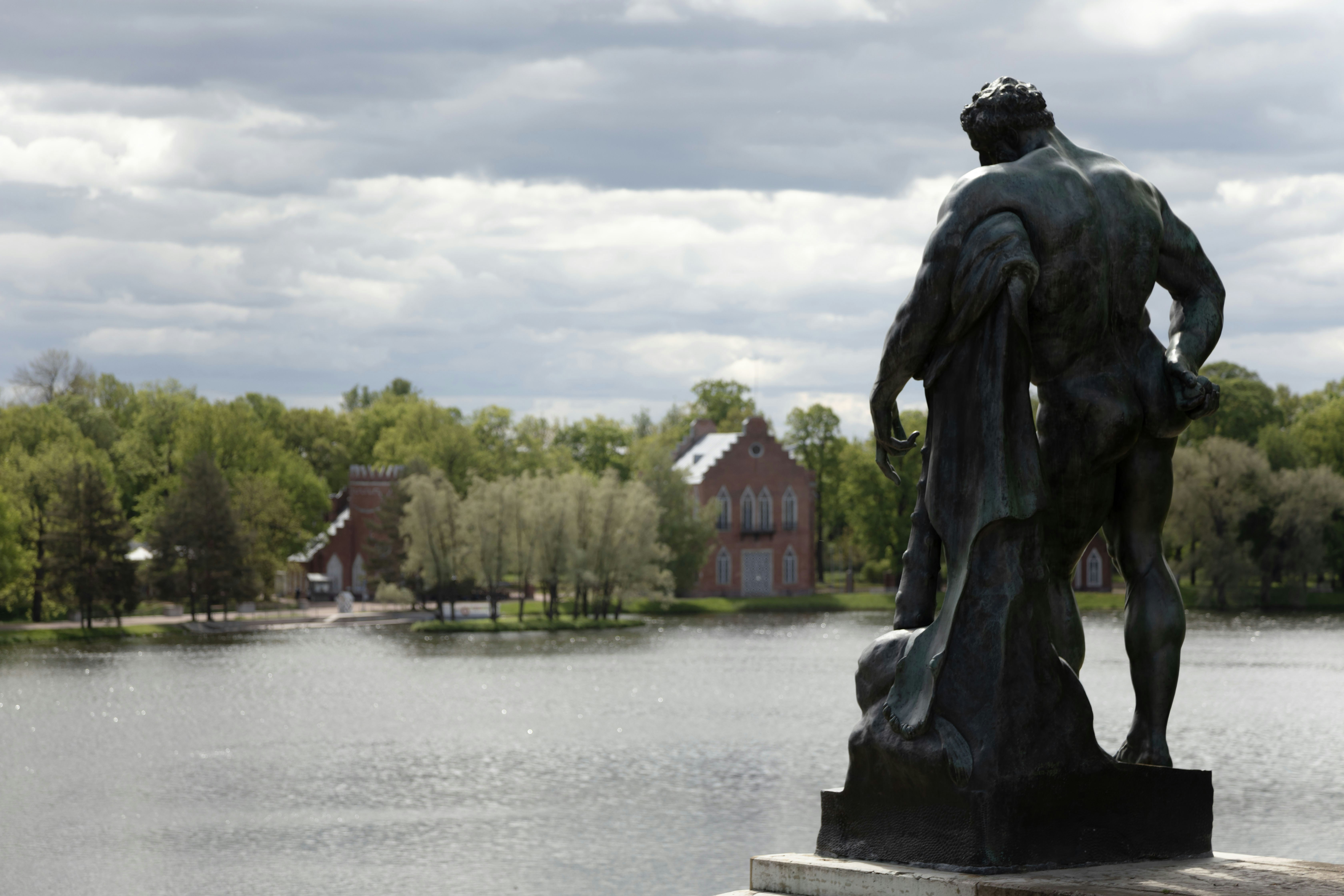 Una estatua se encuentra cerca de un lago y un paisaje exuberante.