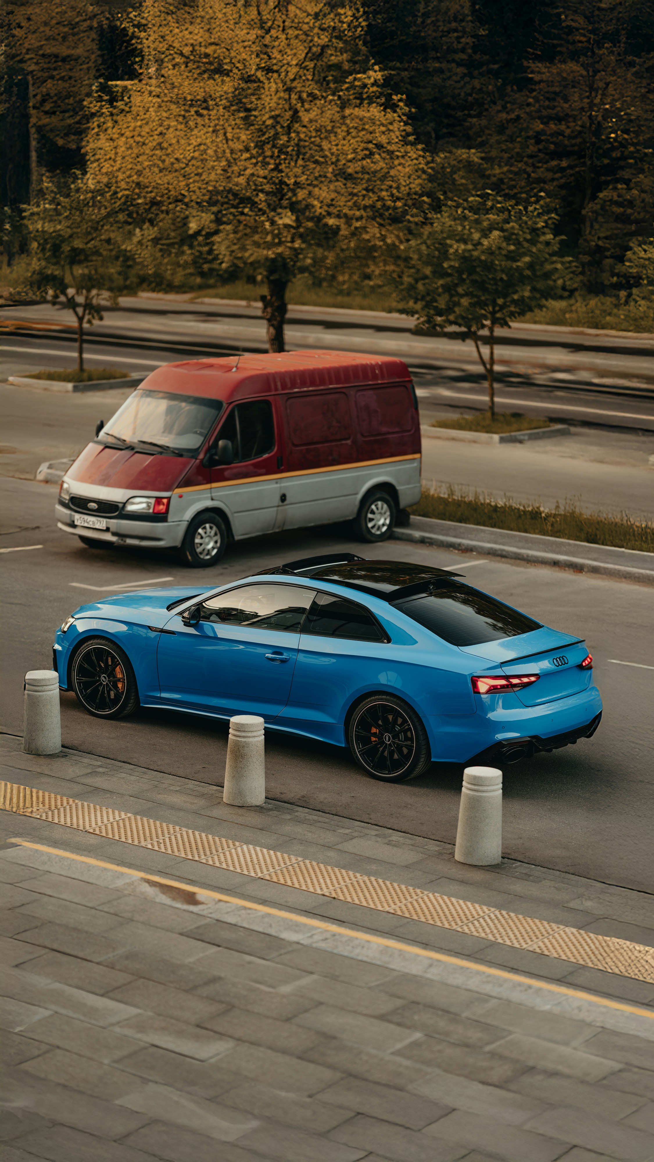 A van and a blue car parked outdoors.