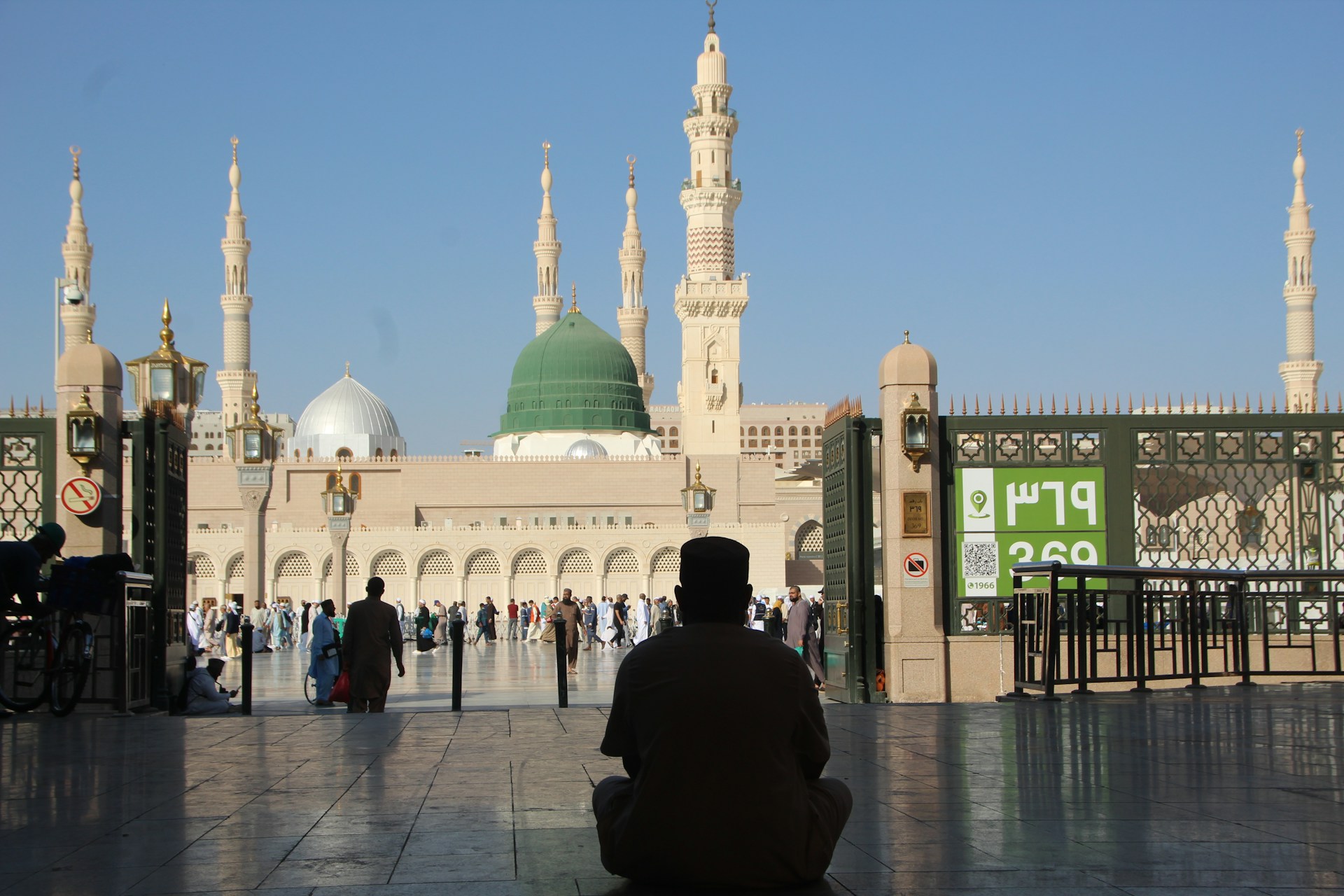A person prays in front of a mosque.