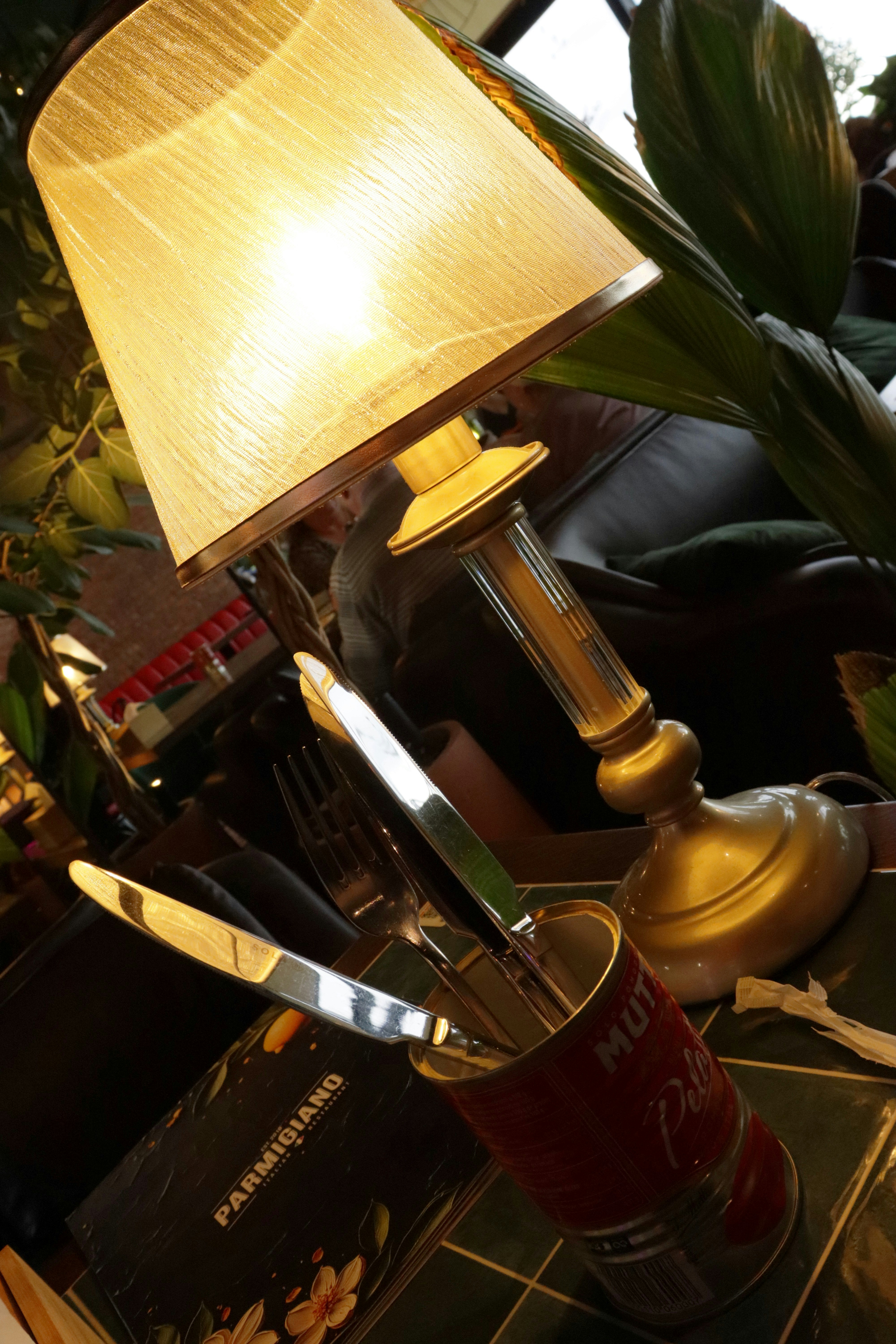 A lamp and cutlery sit on a table.