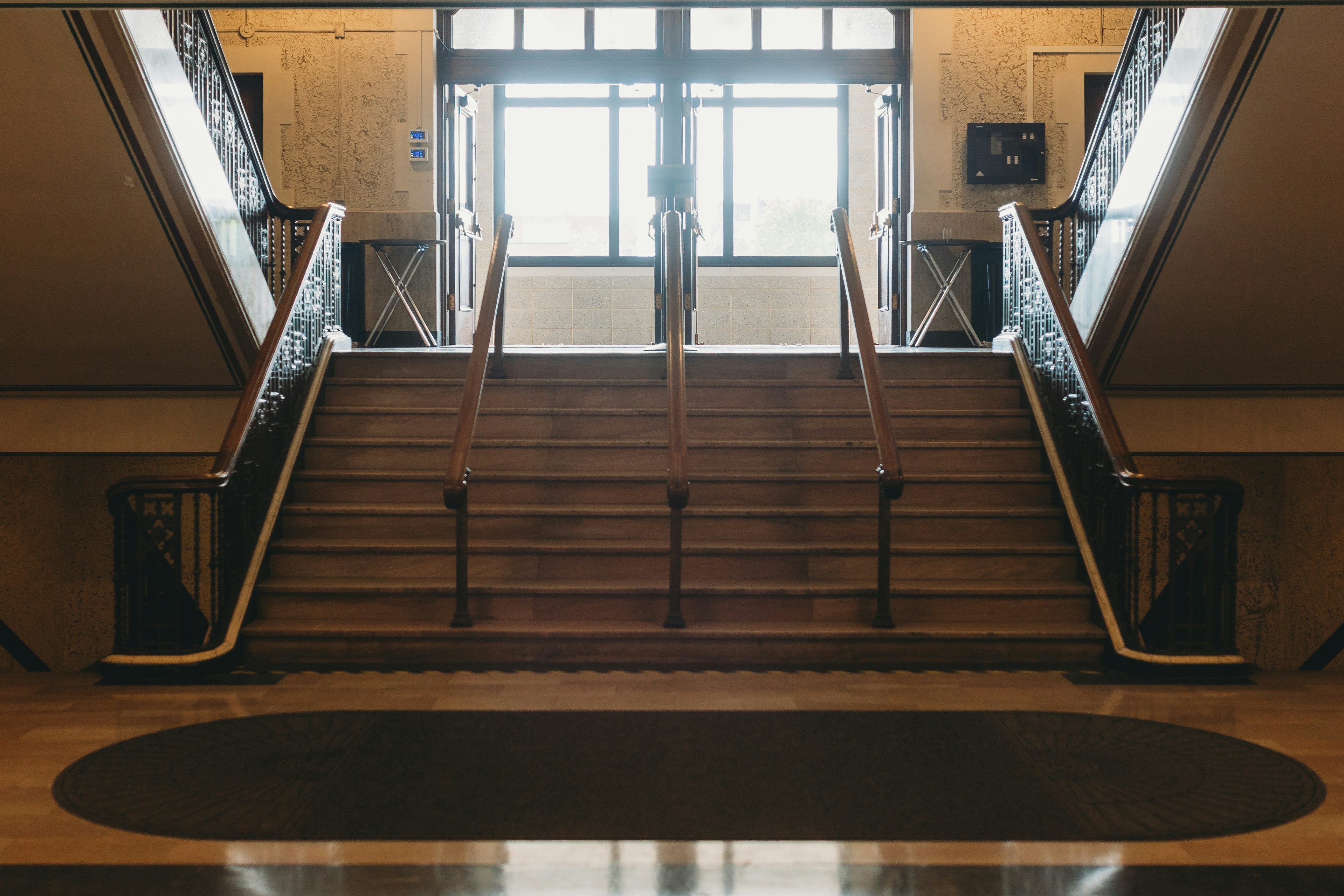A grand wooden staircase leads to a bright door.
