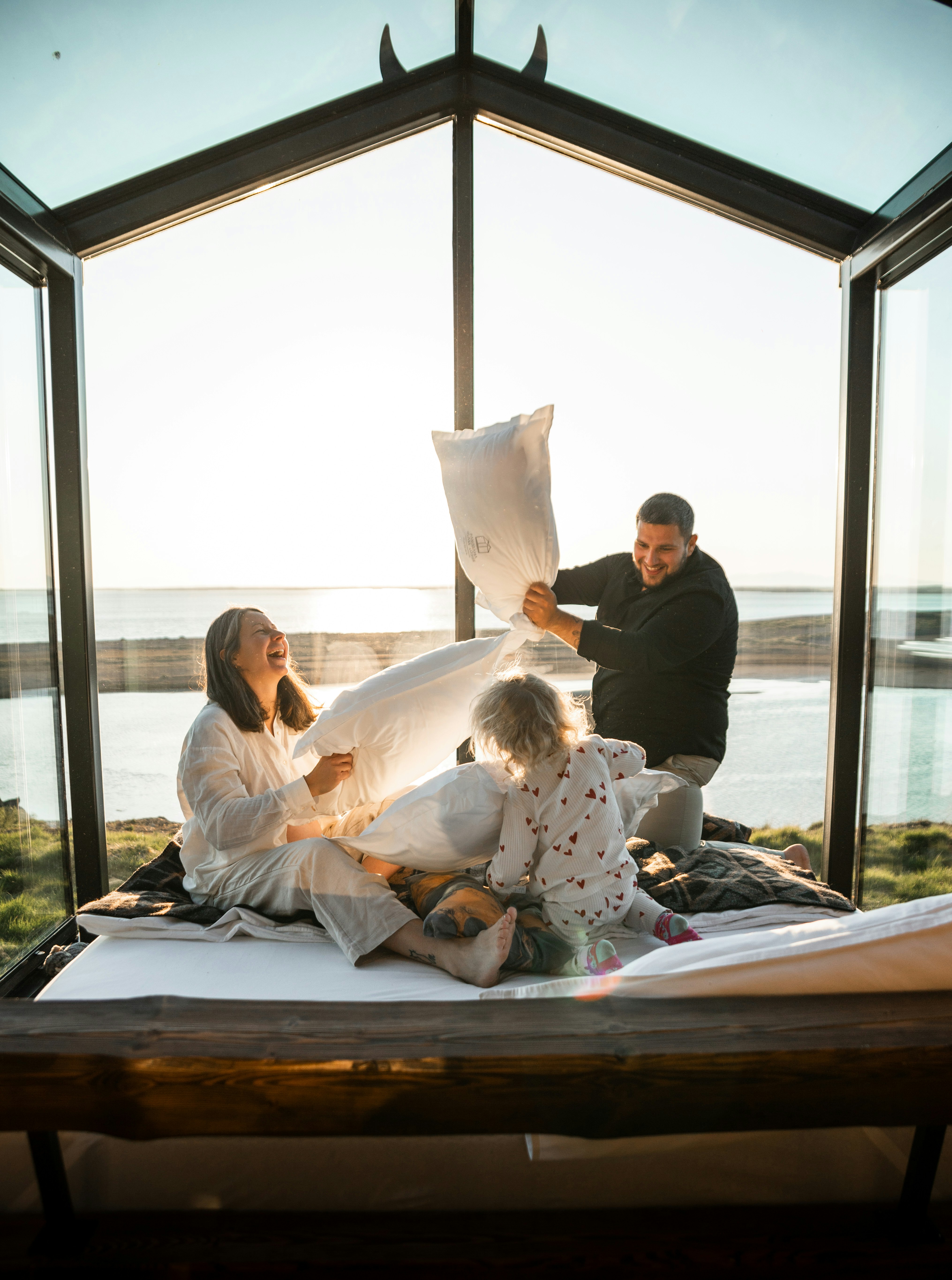 Family enjoys a fun pillow fight inside a glass cabin.