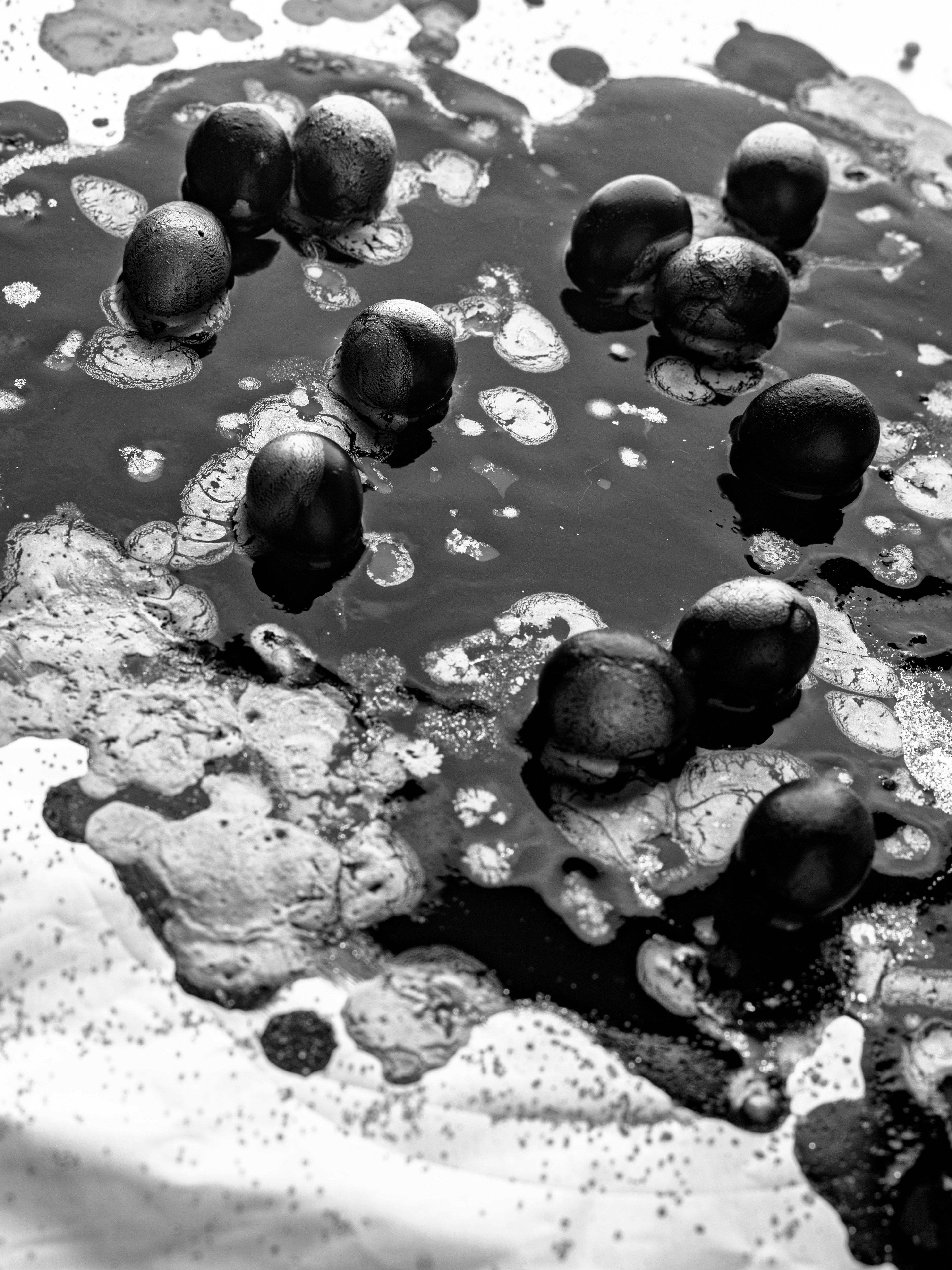 Black nuts float in a pool of dark liquid.