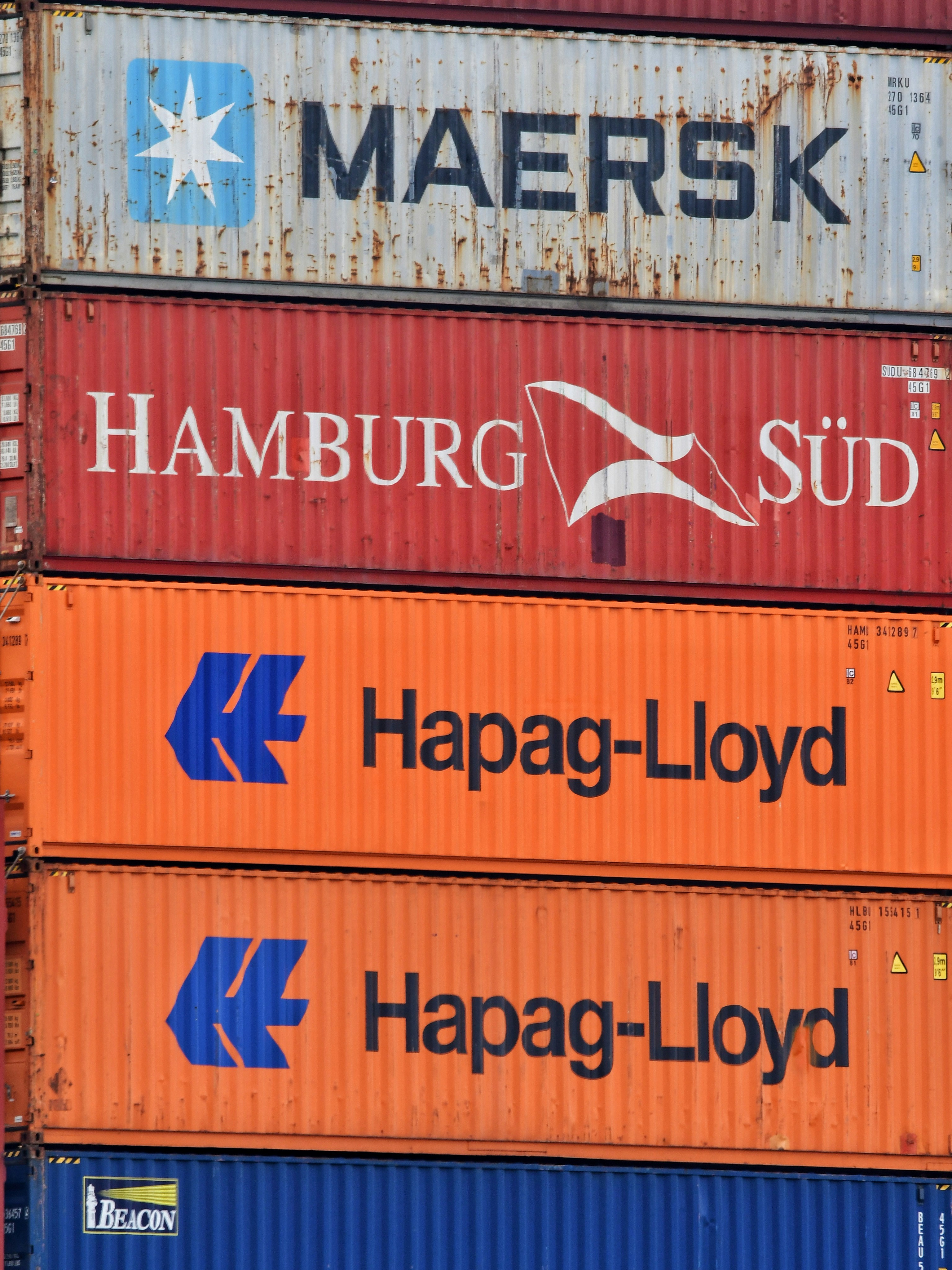 Shipping containers are stacked with company names.