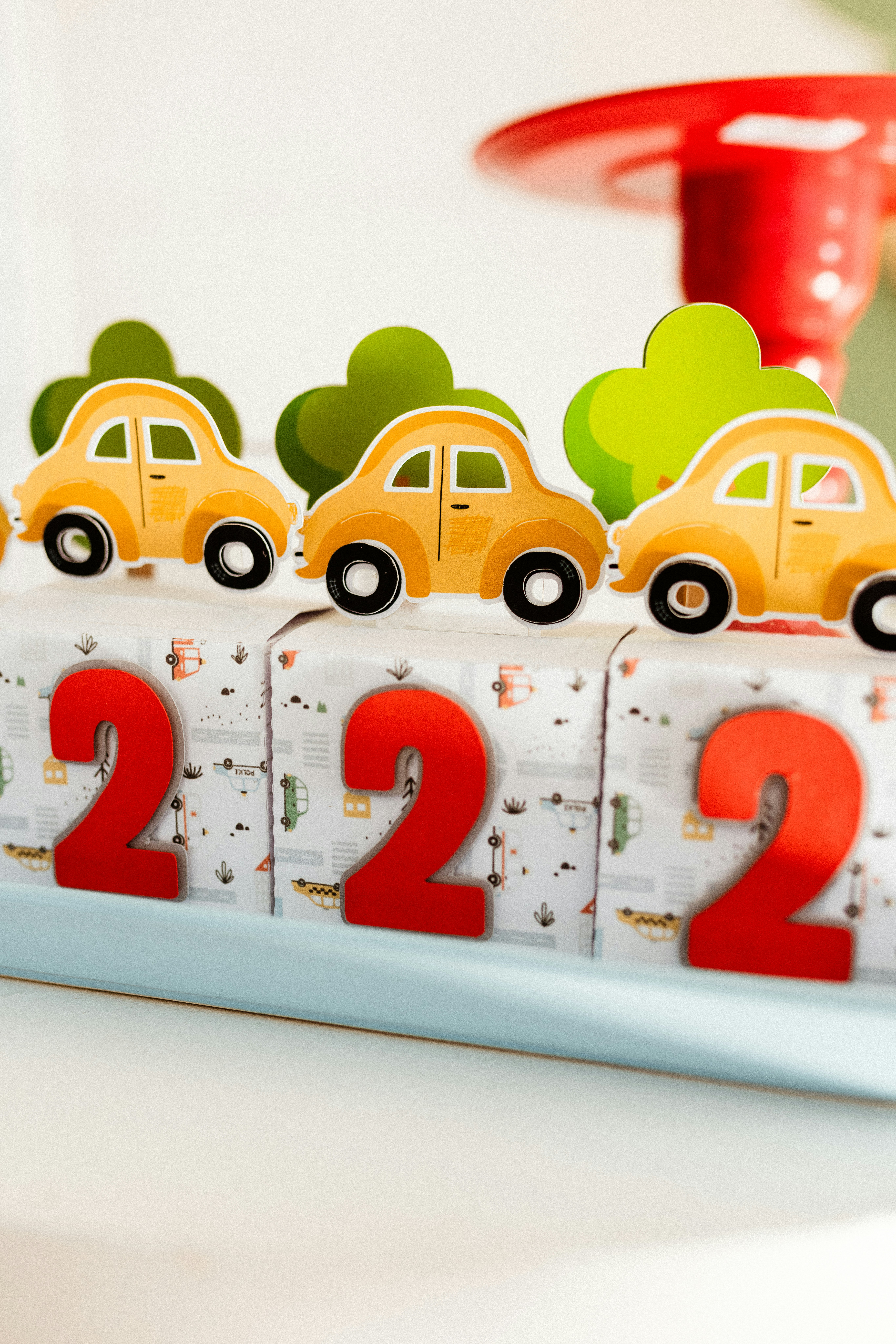 A birthday cake decoration with cars and number twos.