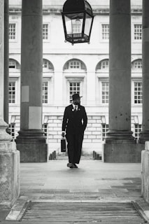 A dapper man walks through a classic building.