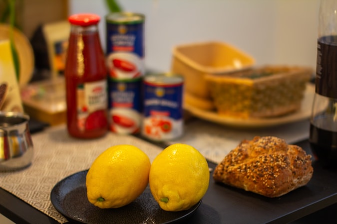 Lemons, croissant, and cans sit on a table.
