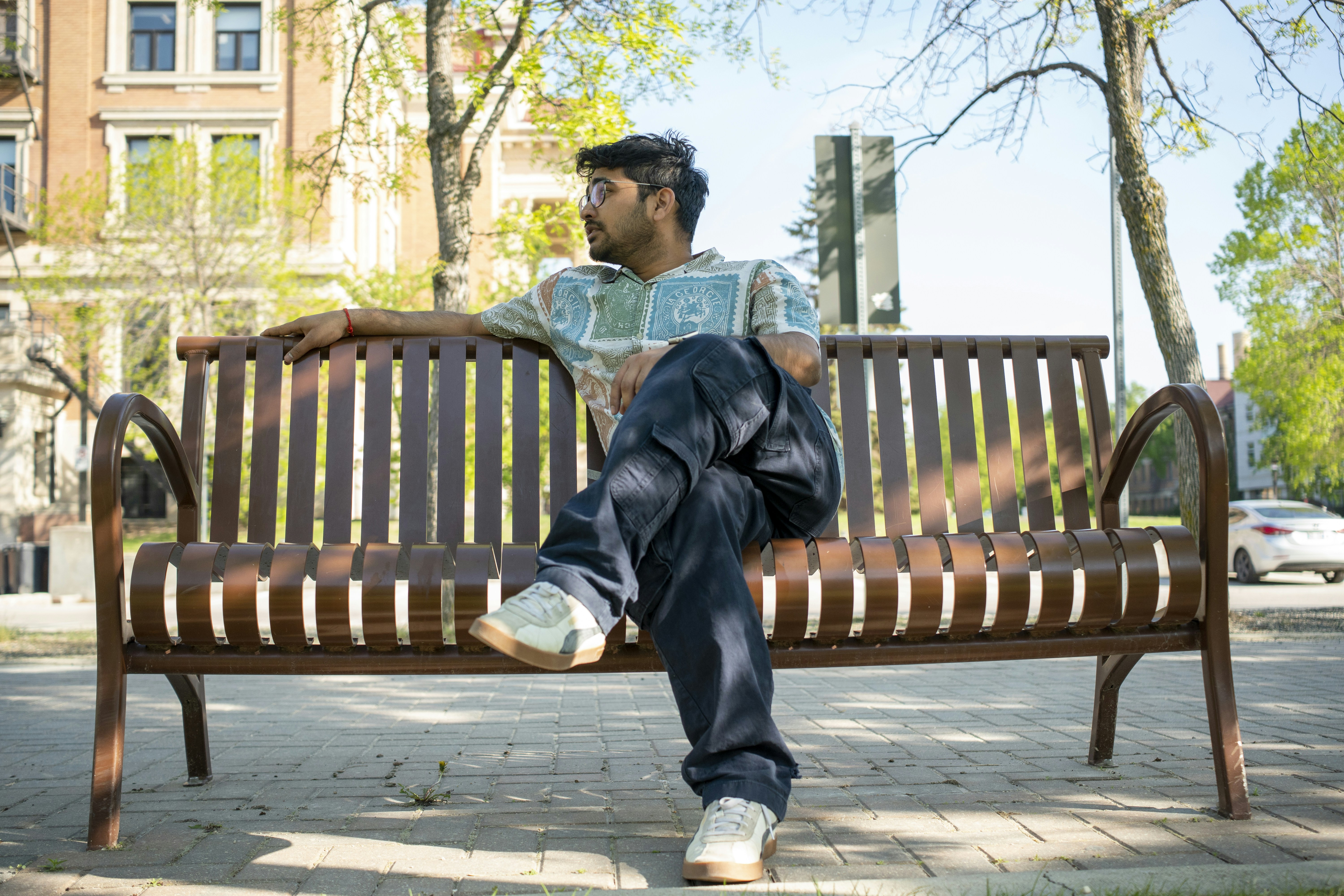 A man sits comfortably on a park bench.