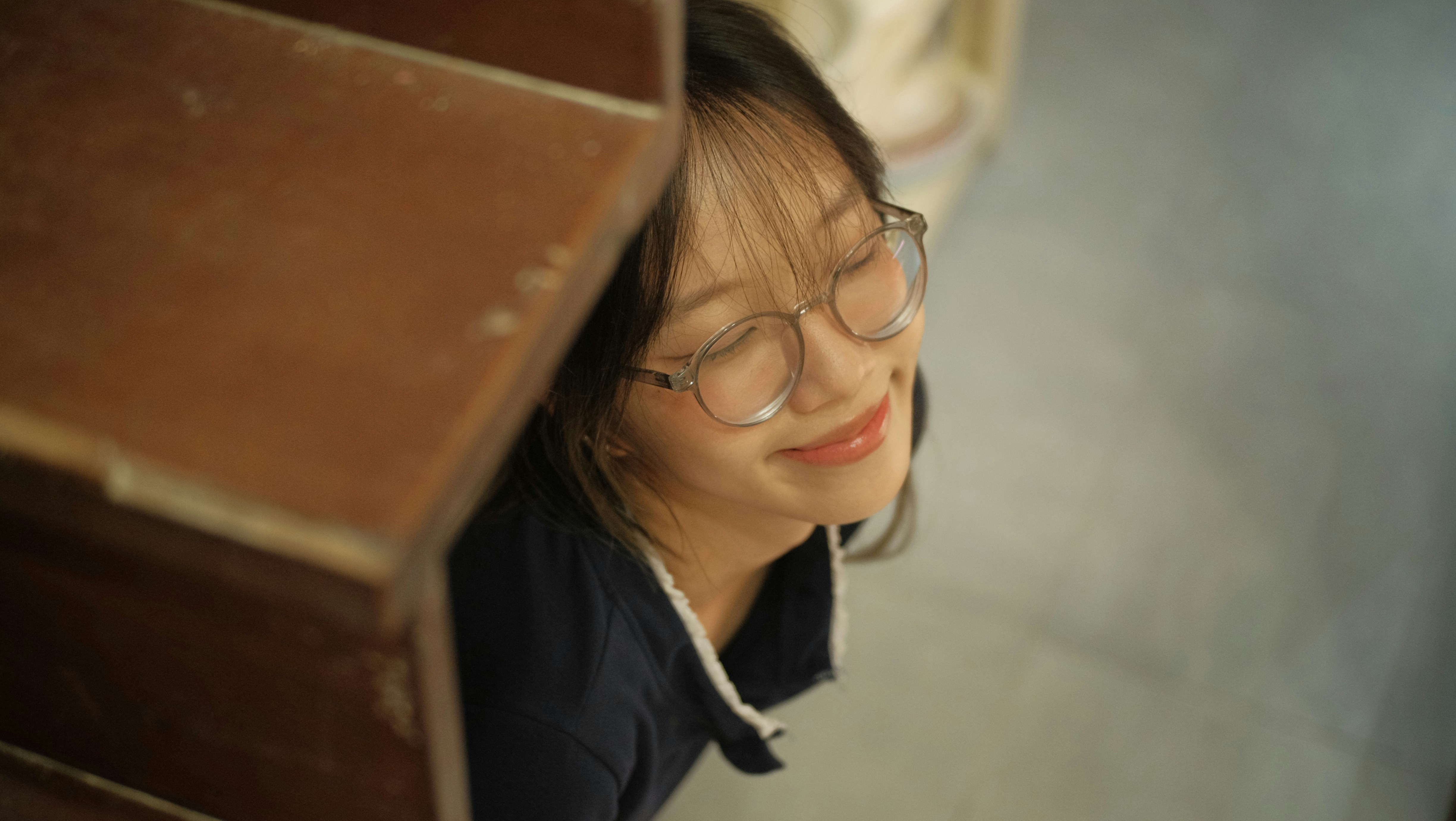 Smiling woman peers out from beside a staircase.