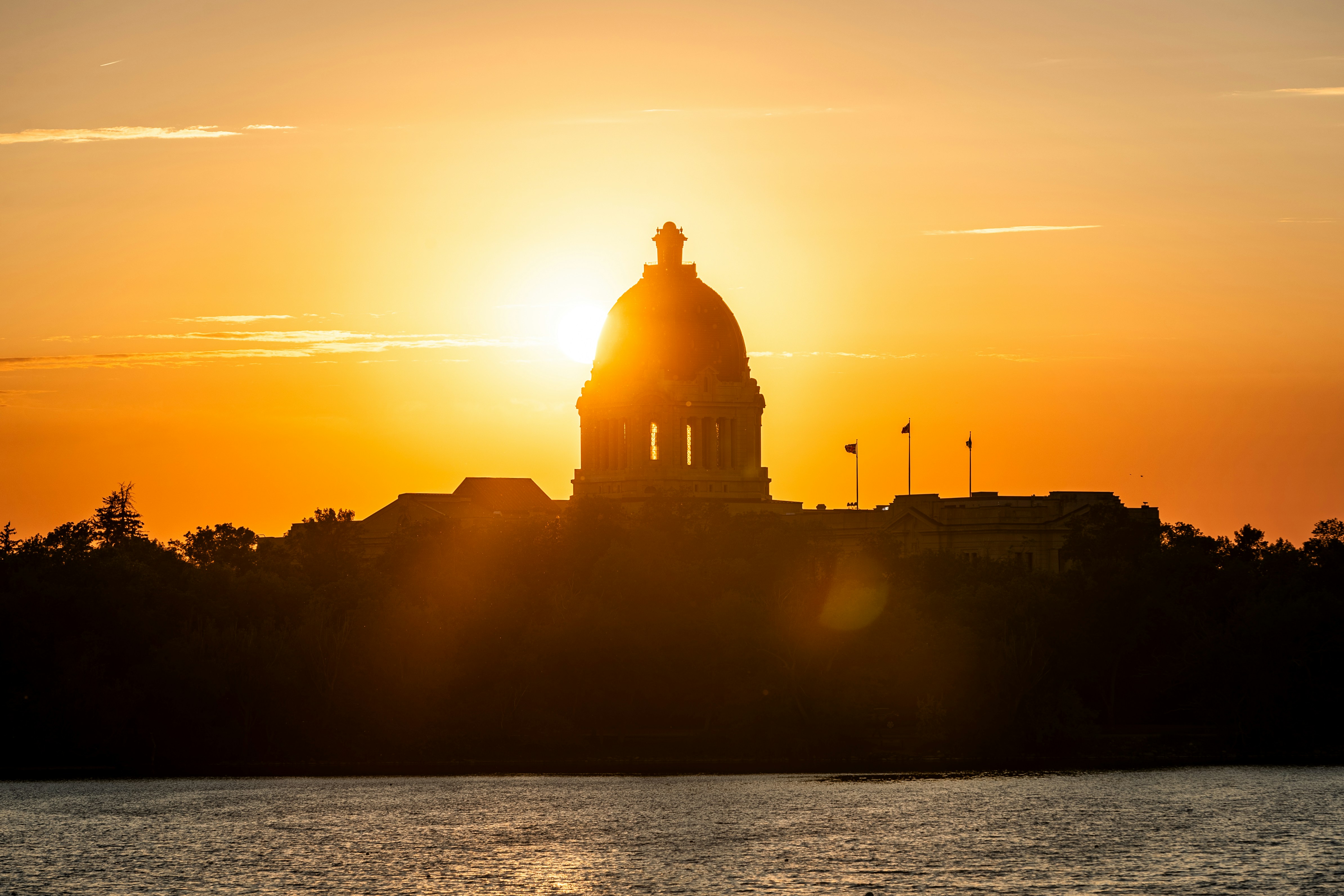 Sunrise silhouettes a building against a bright sky.