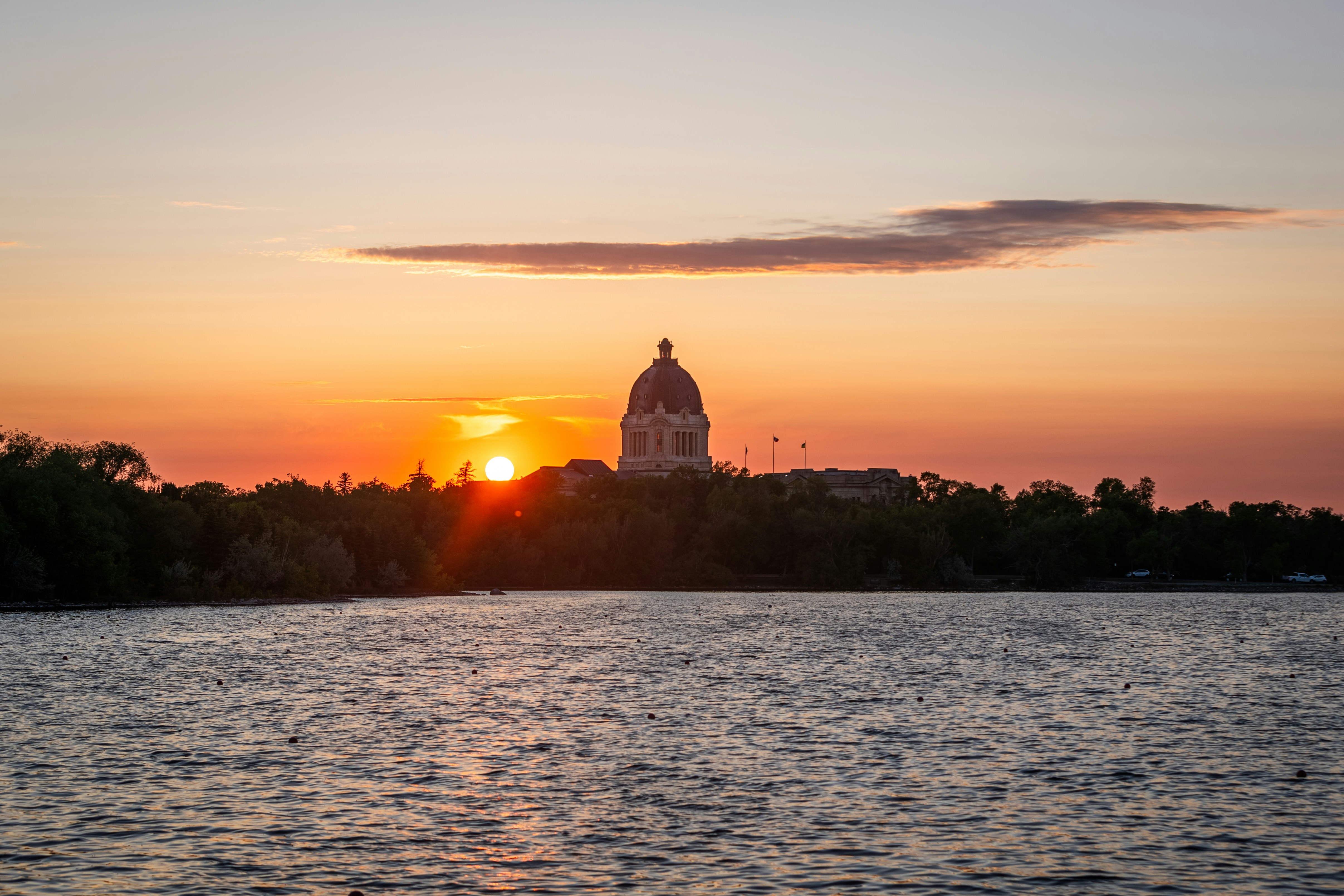Sunset over a city's skyline and water.
