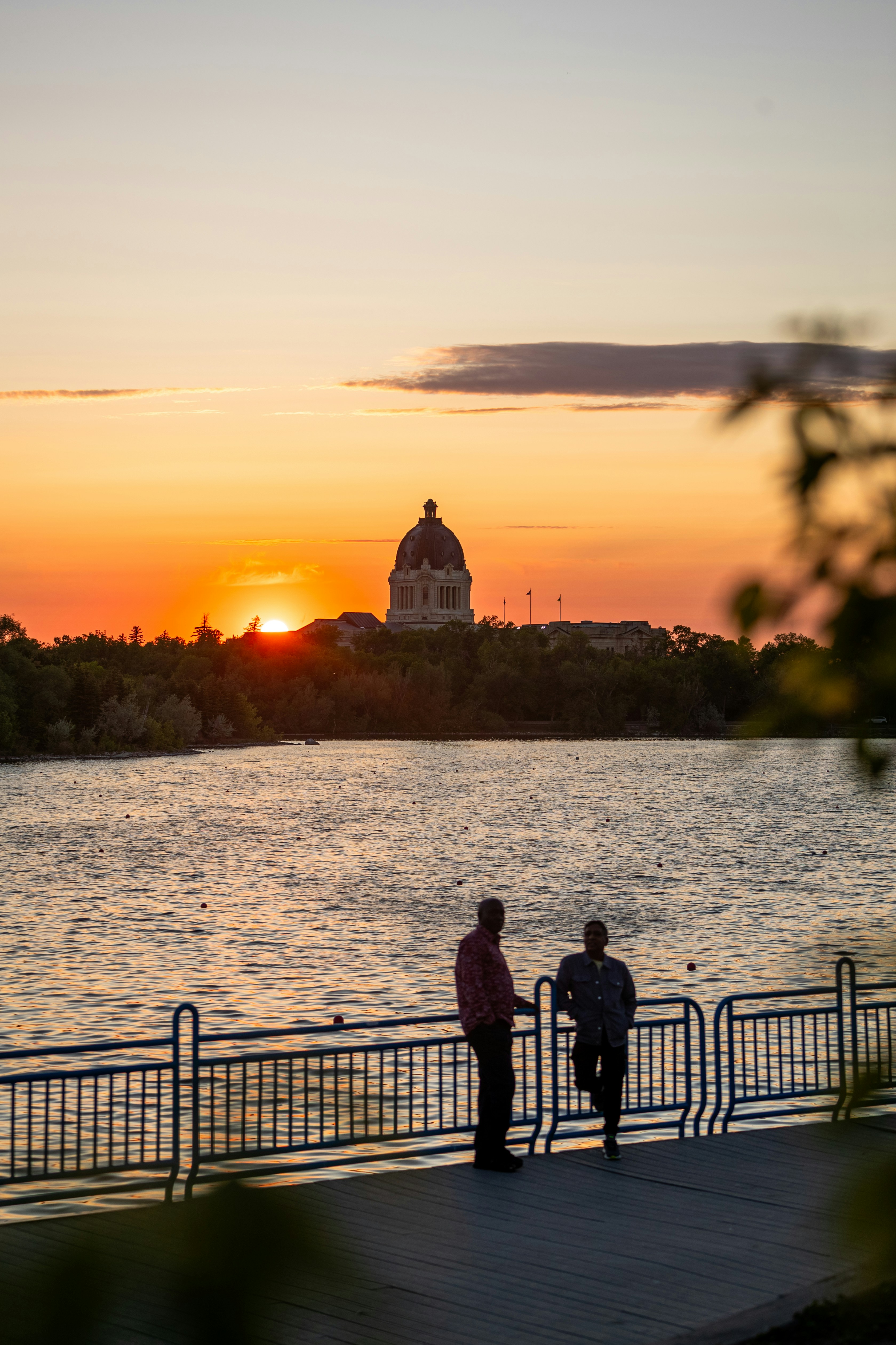 Two people watch the sunset over the water.