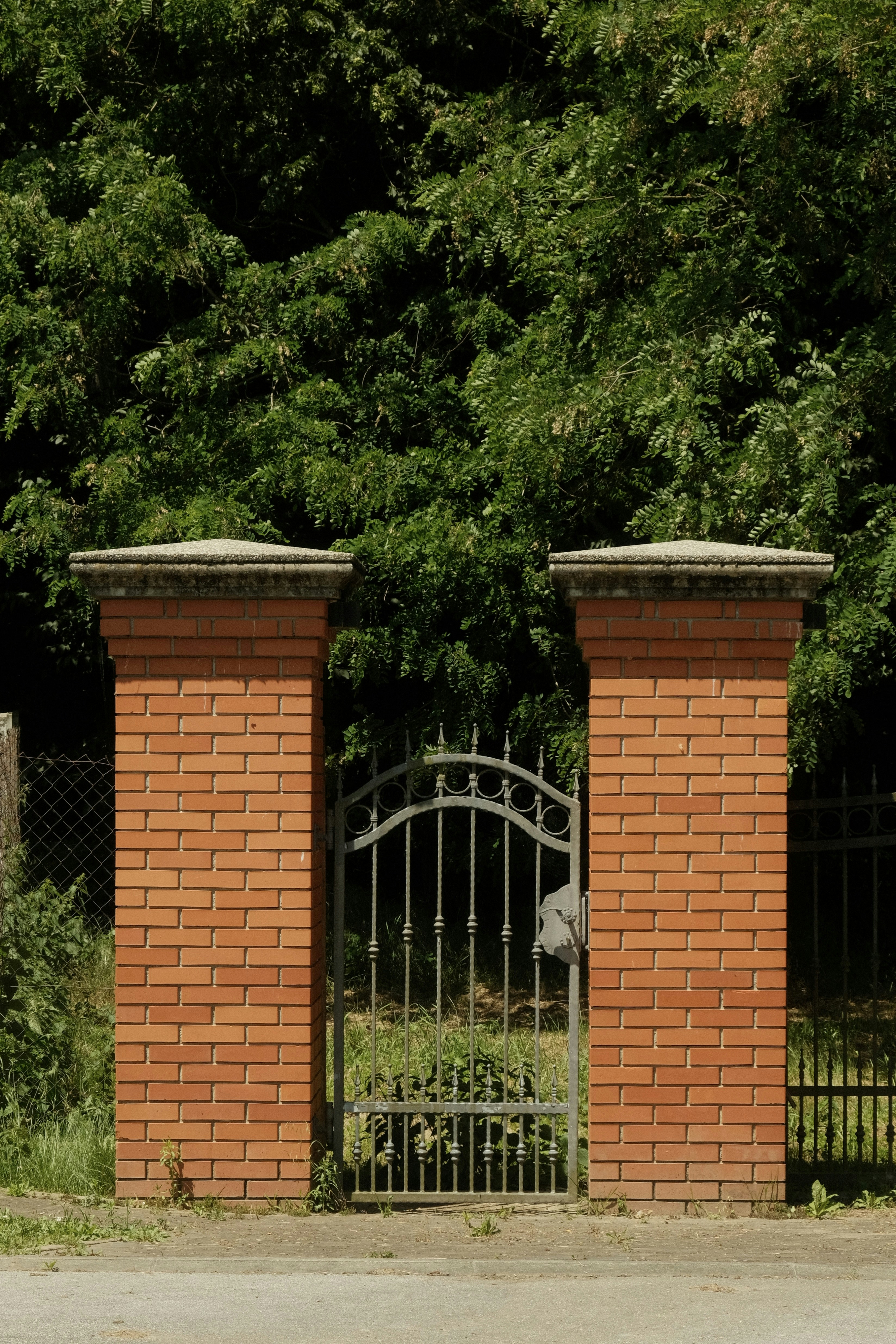 Brick columns frame a wrought-iron gate.