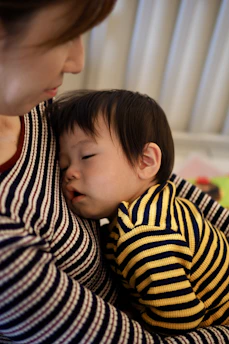 A tired baby sleeps comfortably in mother's arms.