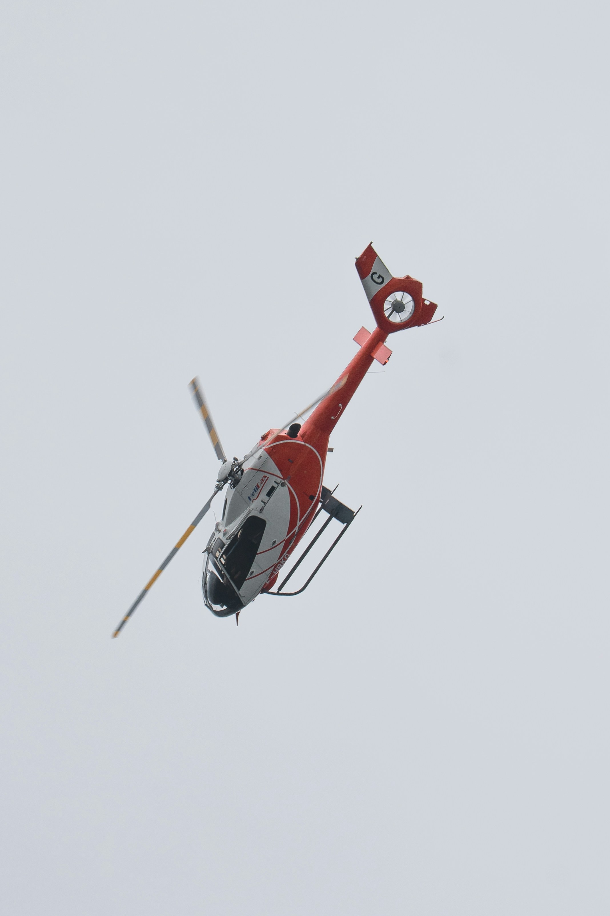 A red and white helicopter flies through the air.