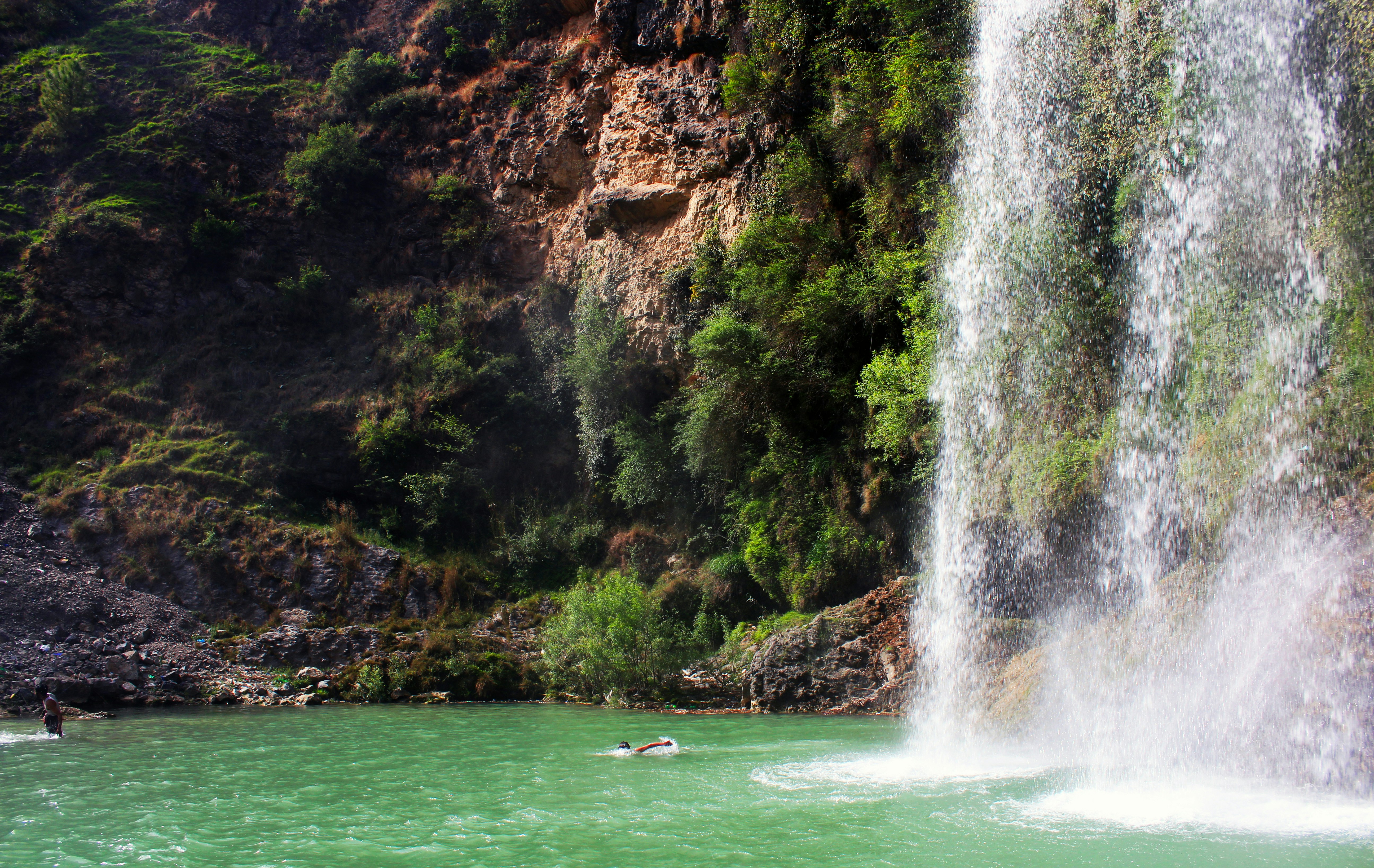 A beautiful waterfall cascades into a serene green pool