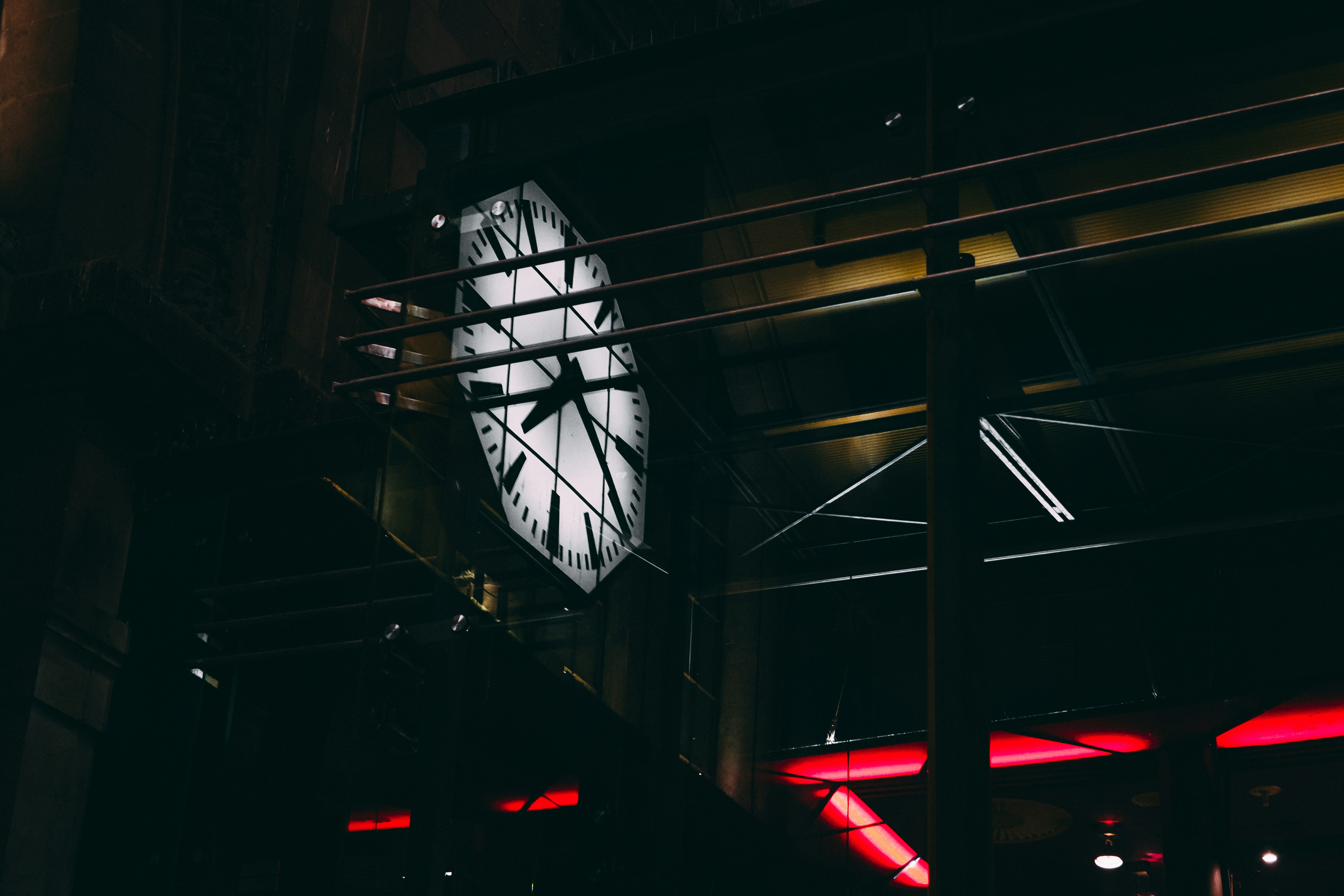 A big clock is illuminated in a dark room.