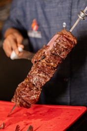 Delicious, grilled steak on a skewer being sliced.