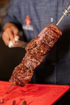 Delicious, grilled steak on a skewer being sliced.