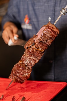 Delicious, grilled steak on a skewer being sliced.
