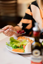 Woman is eating a plate of food with beets.