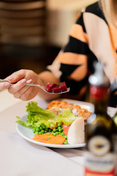 Woman is eating a plate of food with beets.