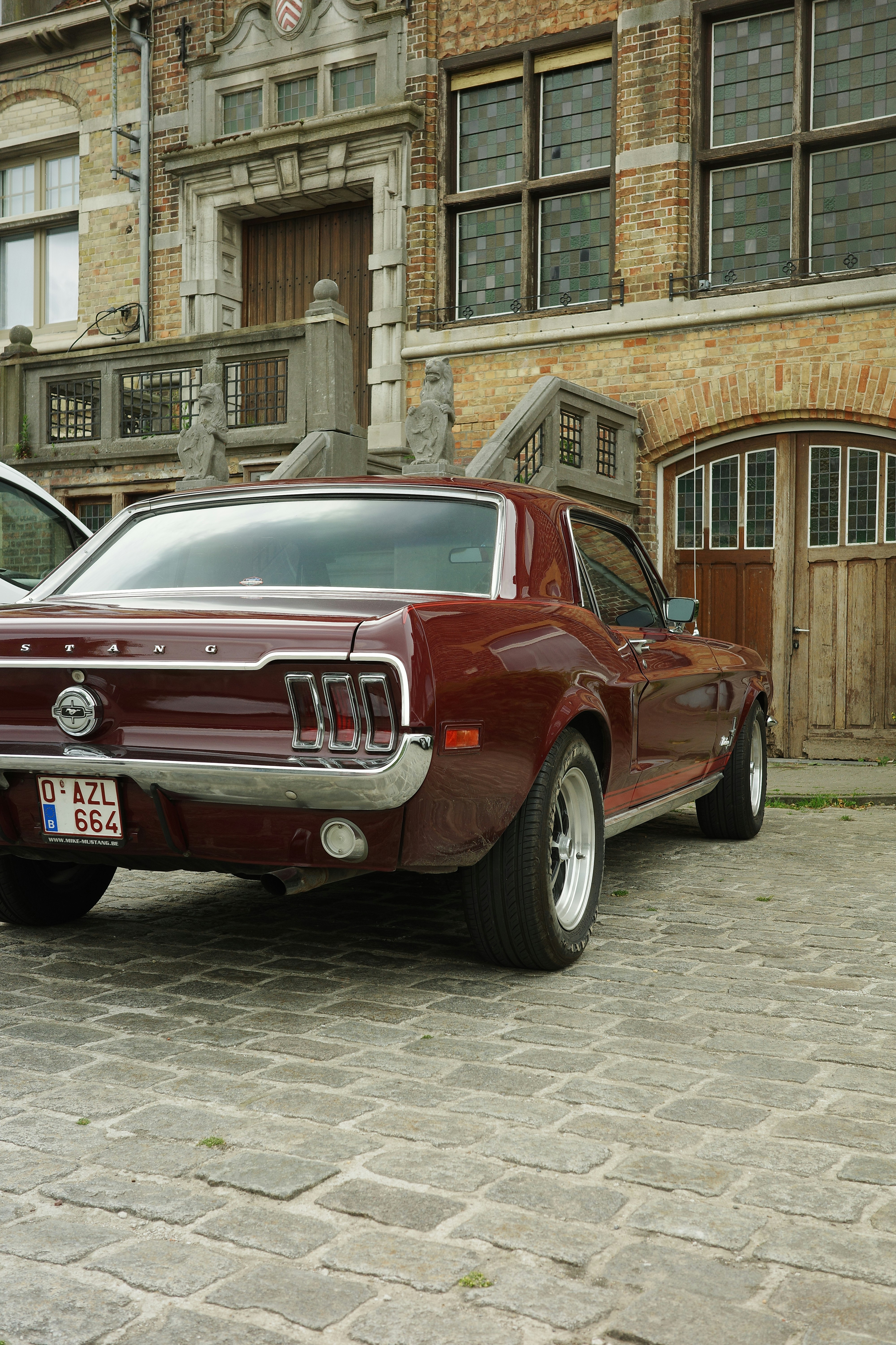 A vintage mustang car is parked near a building.