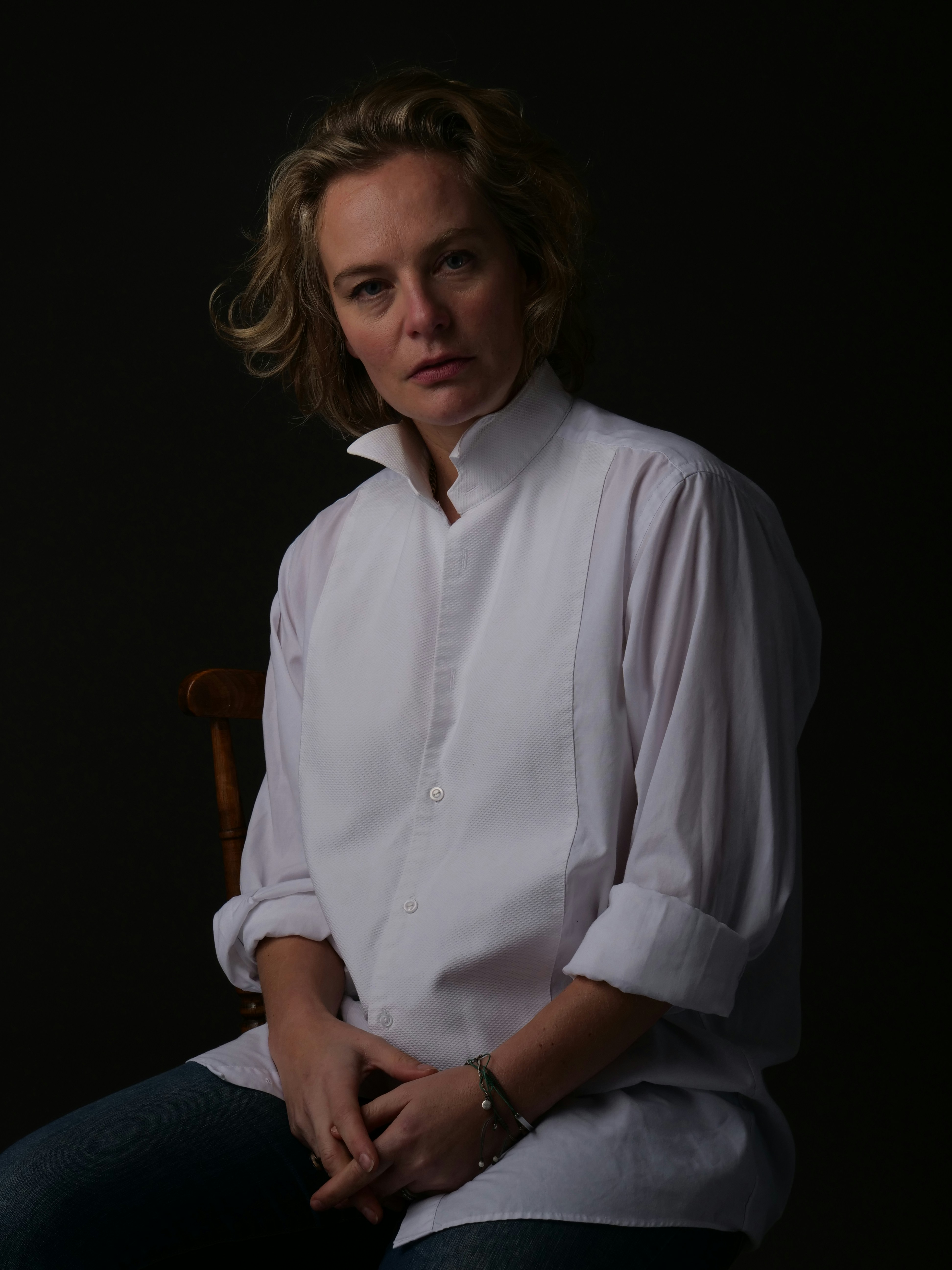 Woman in a white shirt stares pensively.