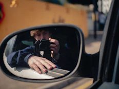 Man takes photo, reflected in a side mirror.