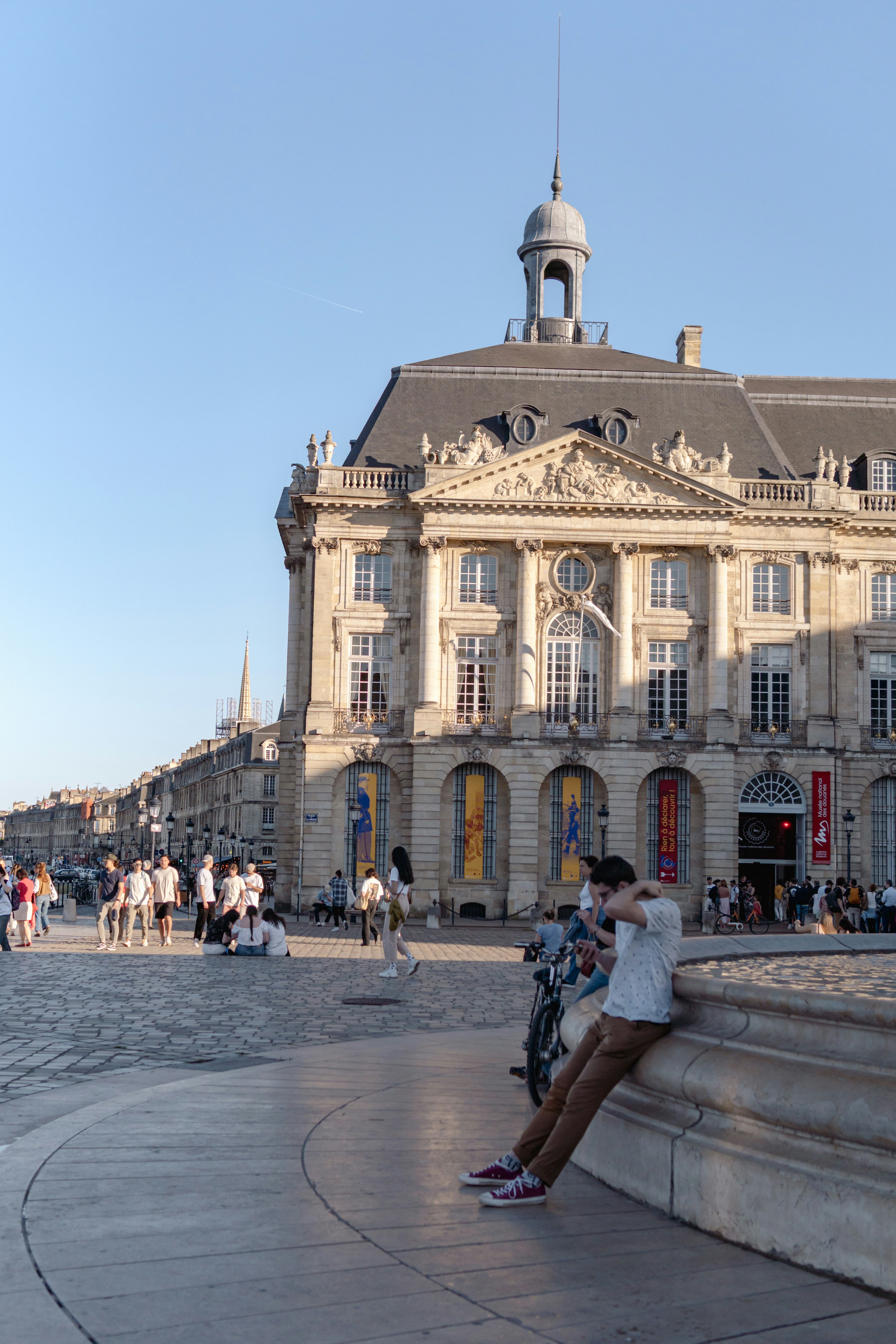 La gente disfruta de la plaza frente a un hermoso edificio.