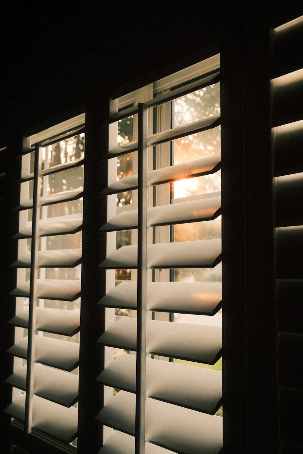 Sunlight streaming through open plantation shutters