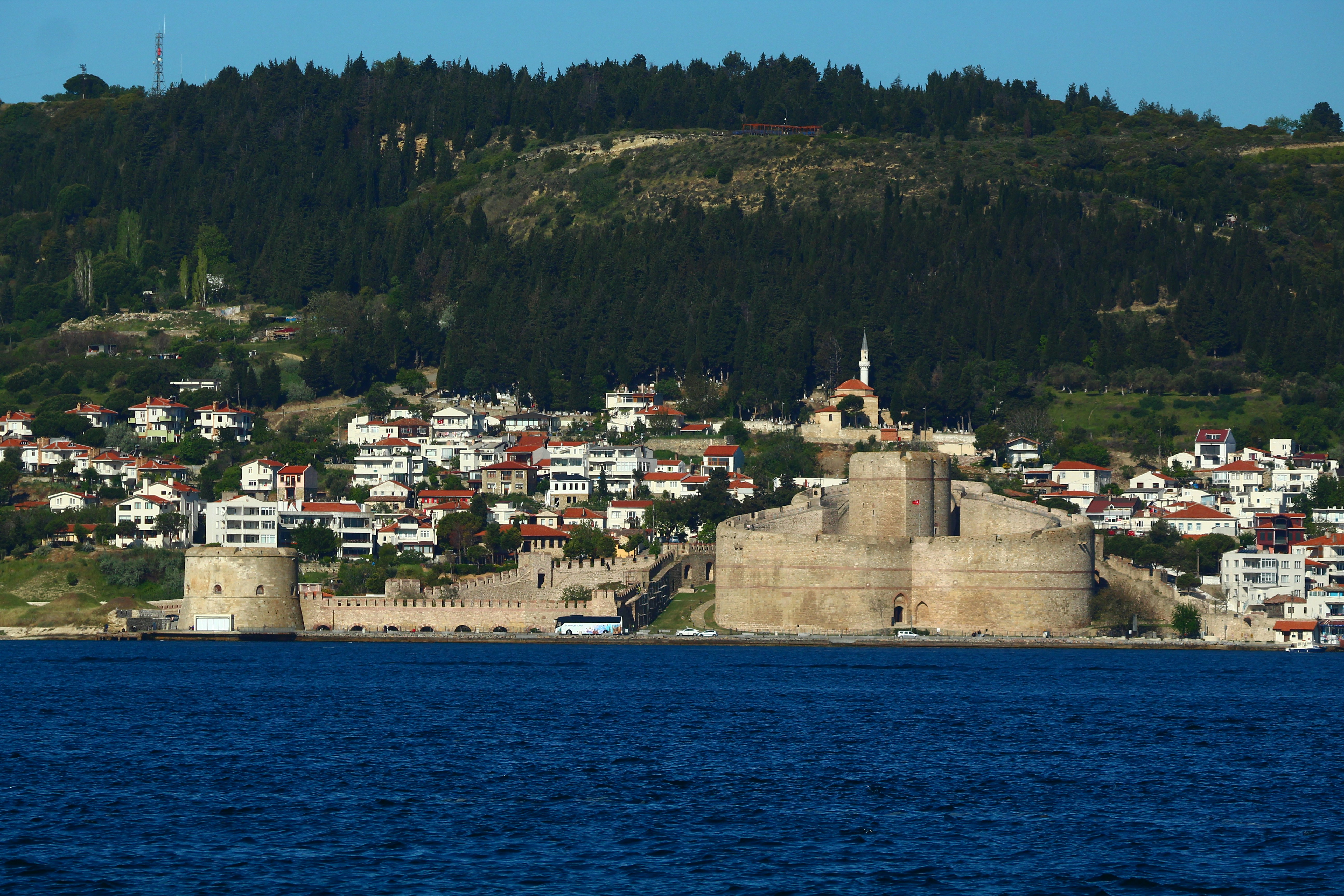 Coastal town with fortress and hillside in the distance.