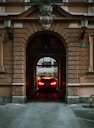 A car is leaving a building through an archway.