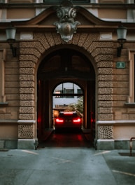 A car is leaving a building through an archway.