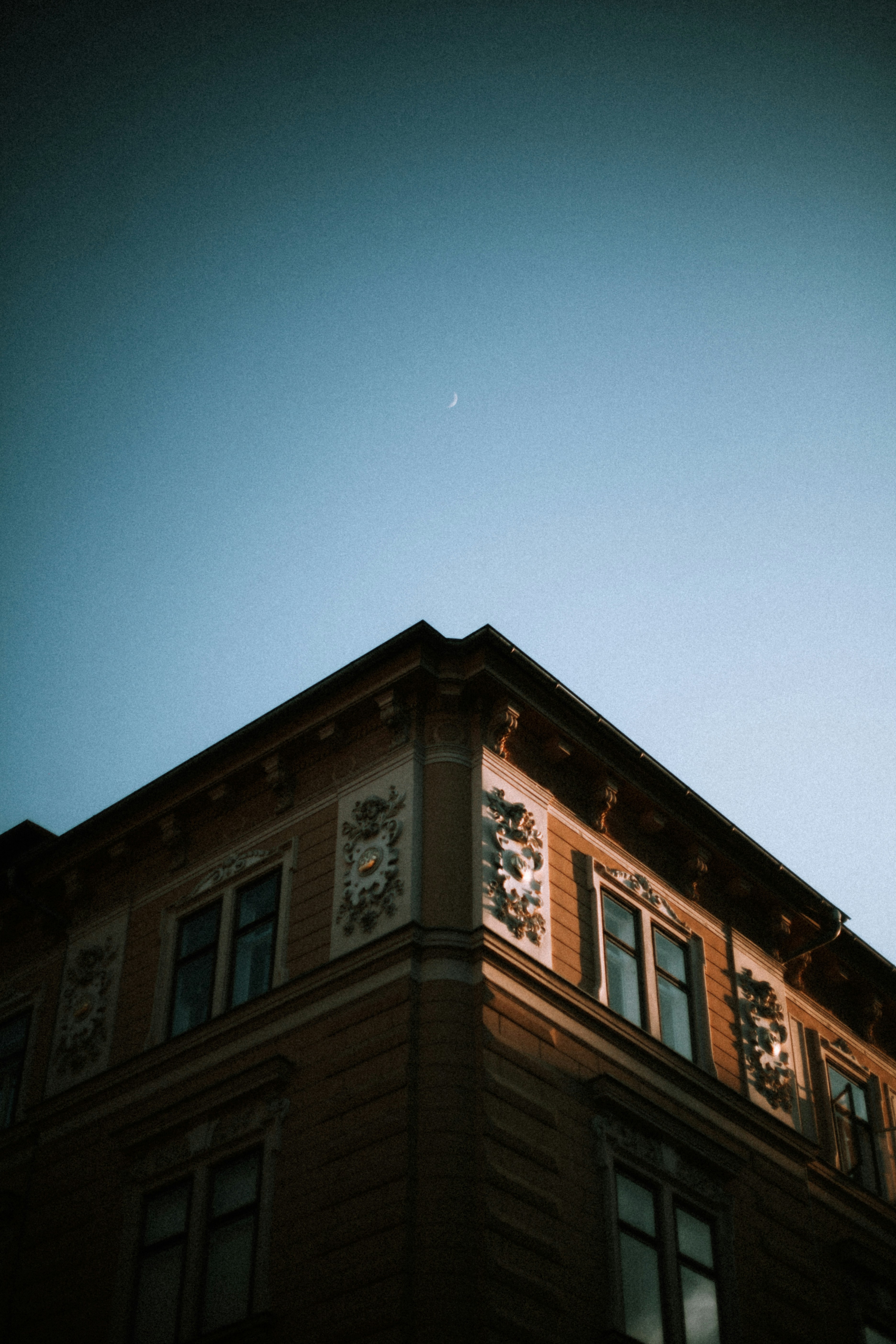 Building corner with a crescent moon in the sky.