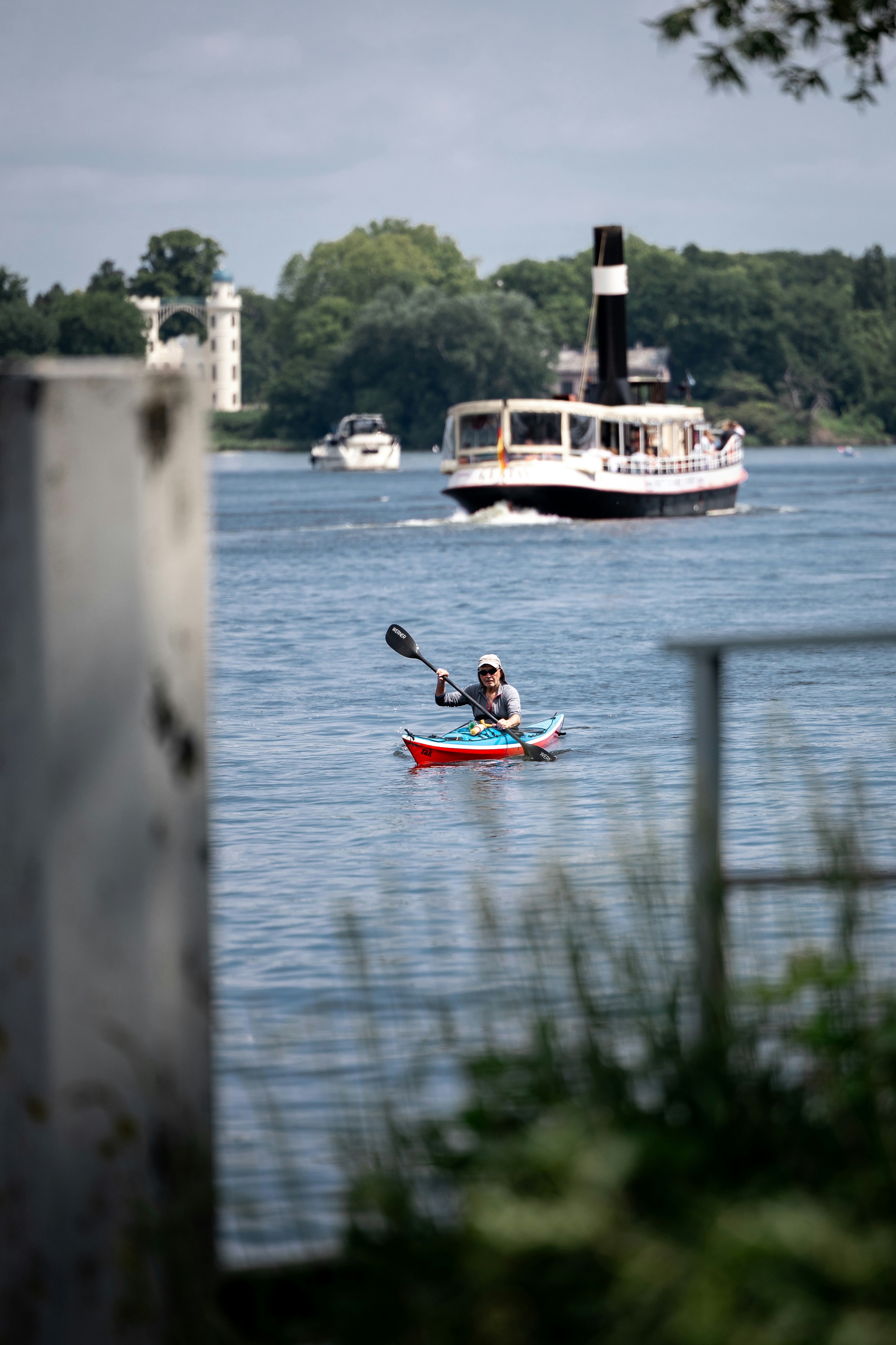 Ein Kajakfahrer paddelt neben einem Boot auf dem Wasser.