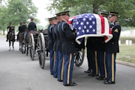 Soldiers carry casket during military funeral.